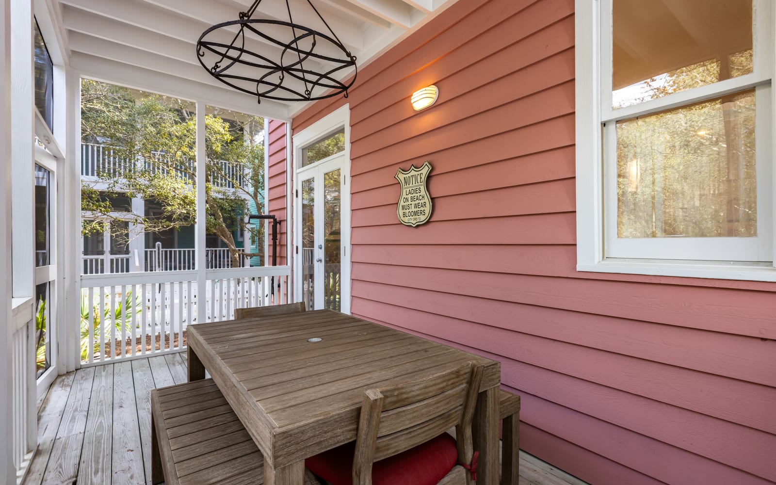 Relax on your charming covered porch with rustic dining table, perfect for morning coffee or evening meals in the peaceful neighborhood setting.
