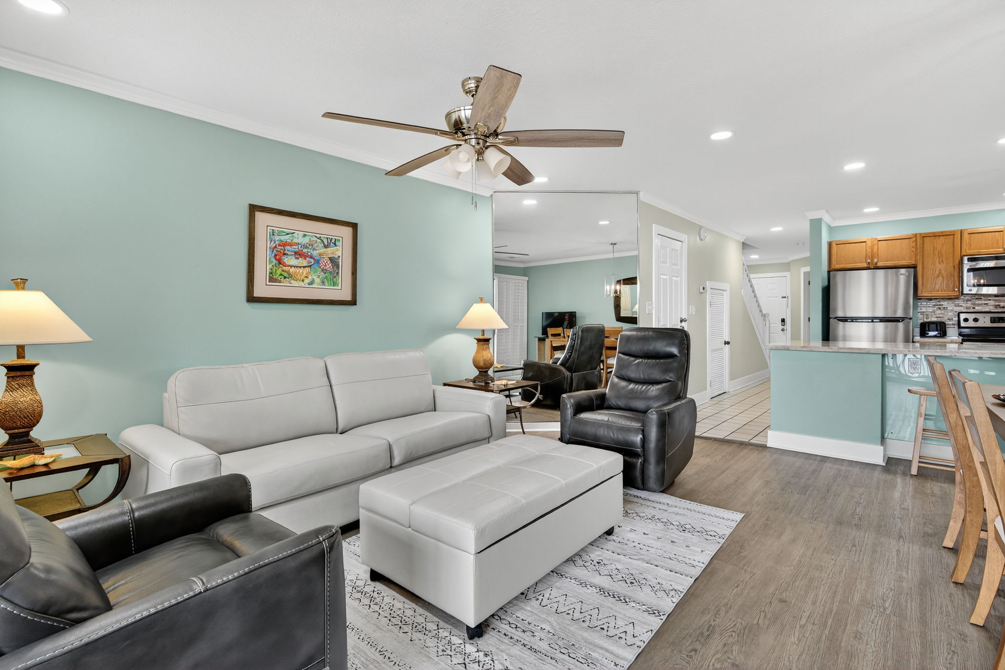 Relax in your spacious living area with comfortable seating, ceiling fan, and open layout that flows seamlessly into the fully equipped kitchen.
