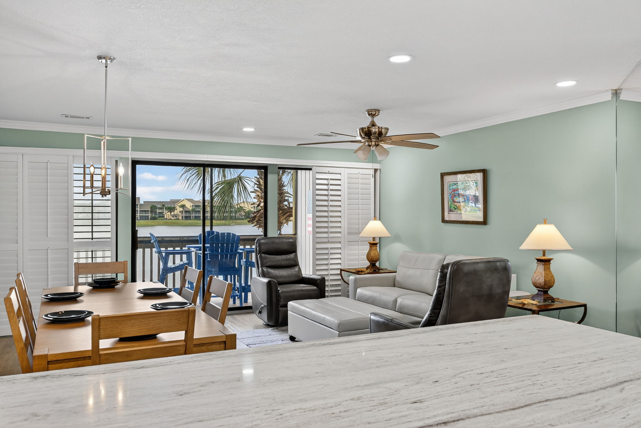 Relax in your spacious living area with comfortable seating, ceiling fan, and stunning waterfront views through sliding glass doors leading to your private balcony.