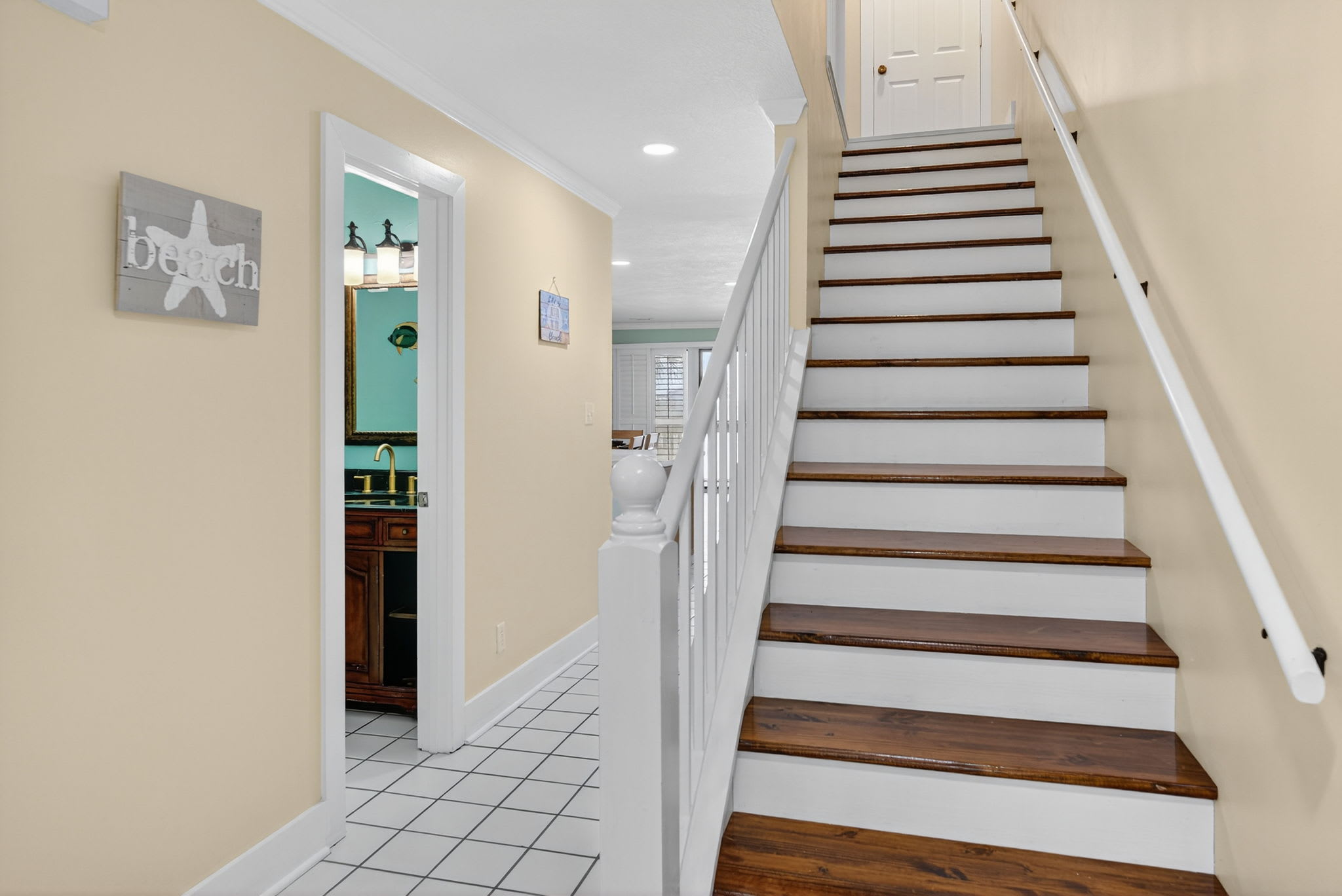 Ascend the beautiful wooden staircase to your upper level, with glimpses of the charming kitchen awaiting your culinary adventures below.