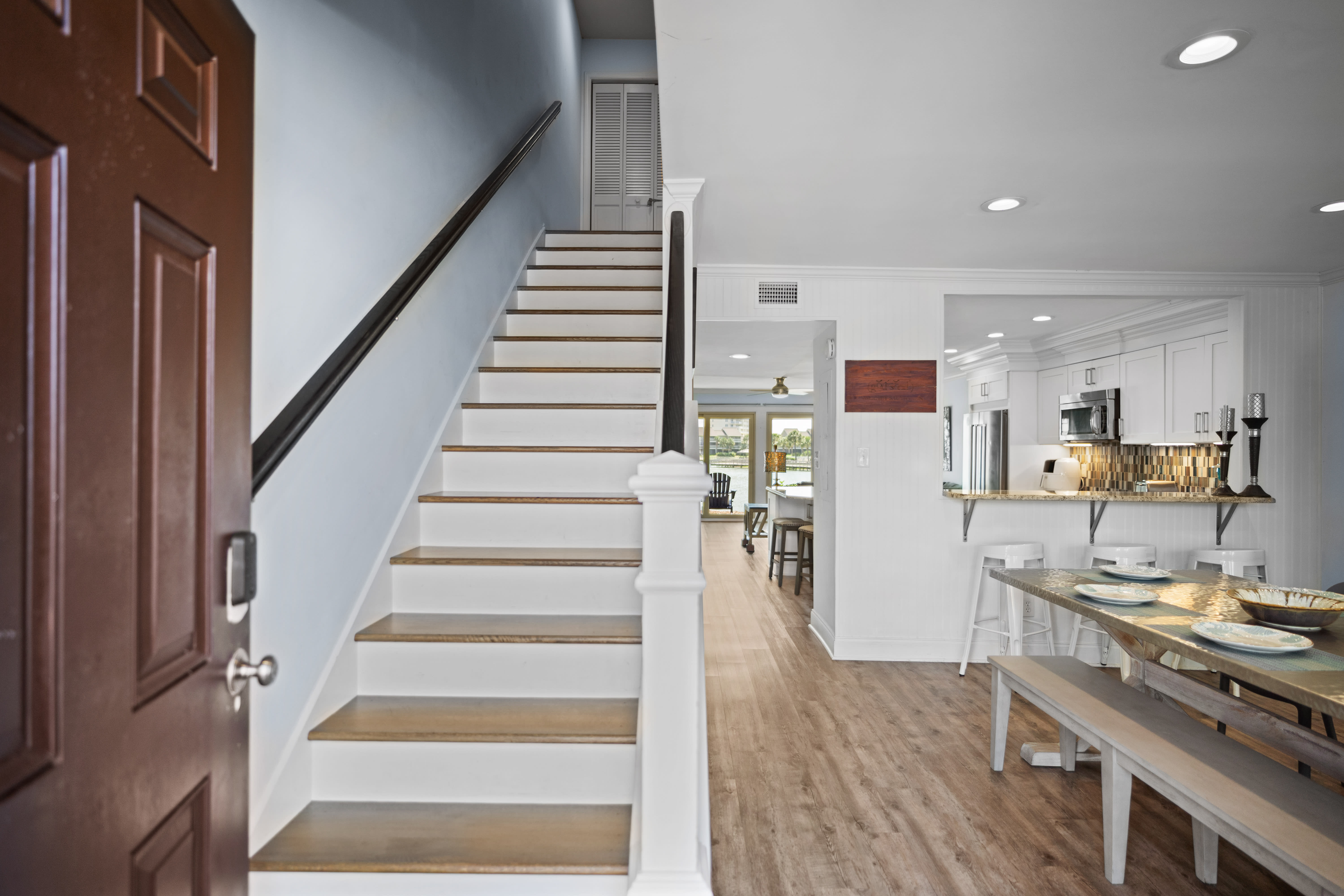 Bright entryway featuring LVP wood floors, and an open layout leading to a modern kitchen and living area with lake views. Clean, airy, and inviting.