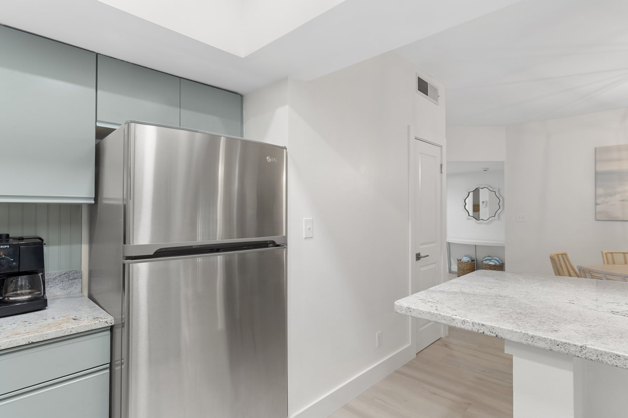 This kitchen nook features wood cabinetry, granite counters, and a sleek stainless-steel refrigerator.