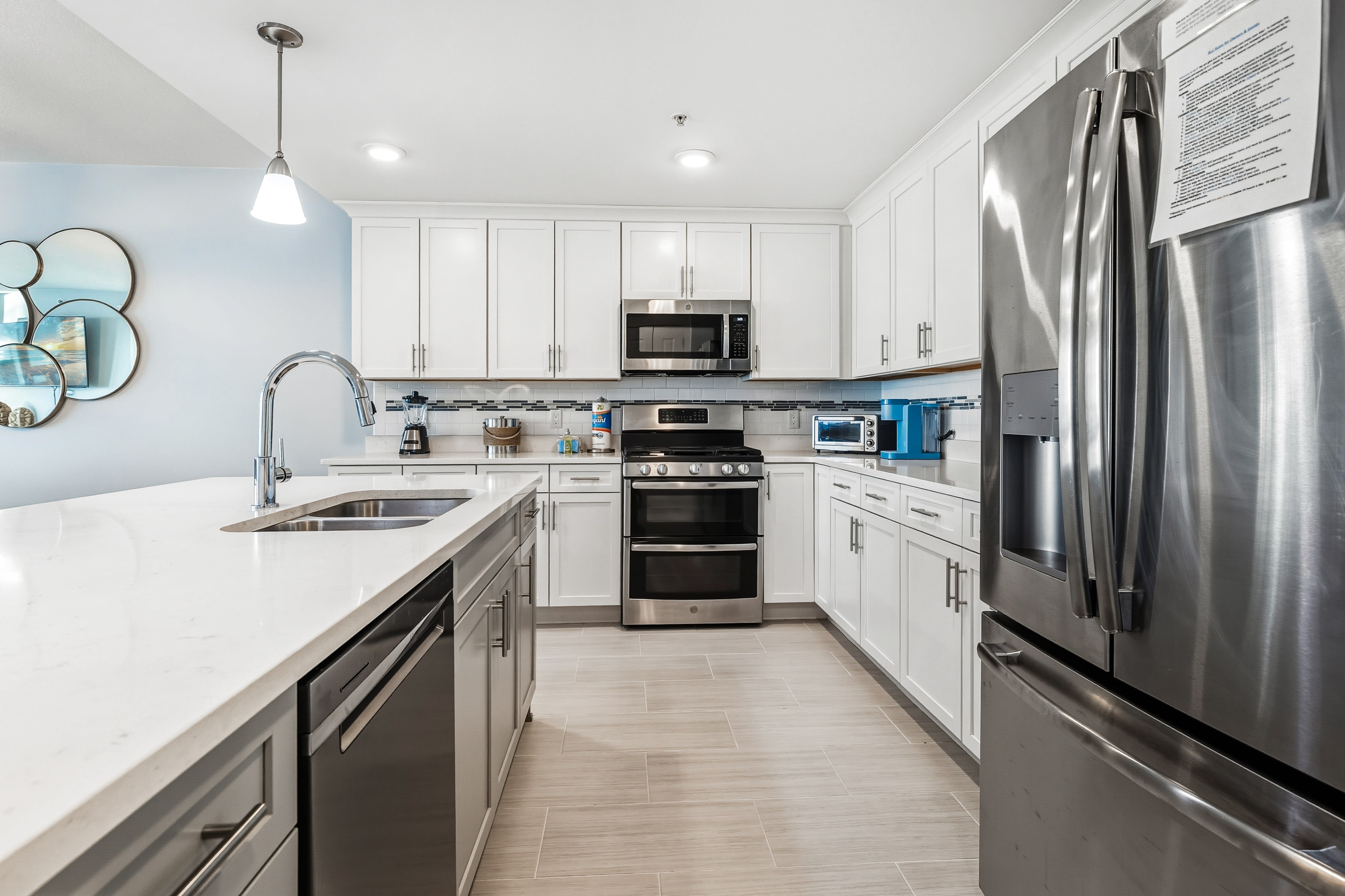 Your modern kitchen features gleaming white cabinets, stainless steel appliances, and spacious quartz countertops perfect for preparing memorable meals during your stay.