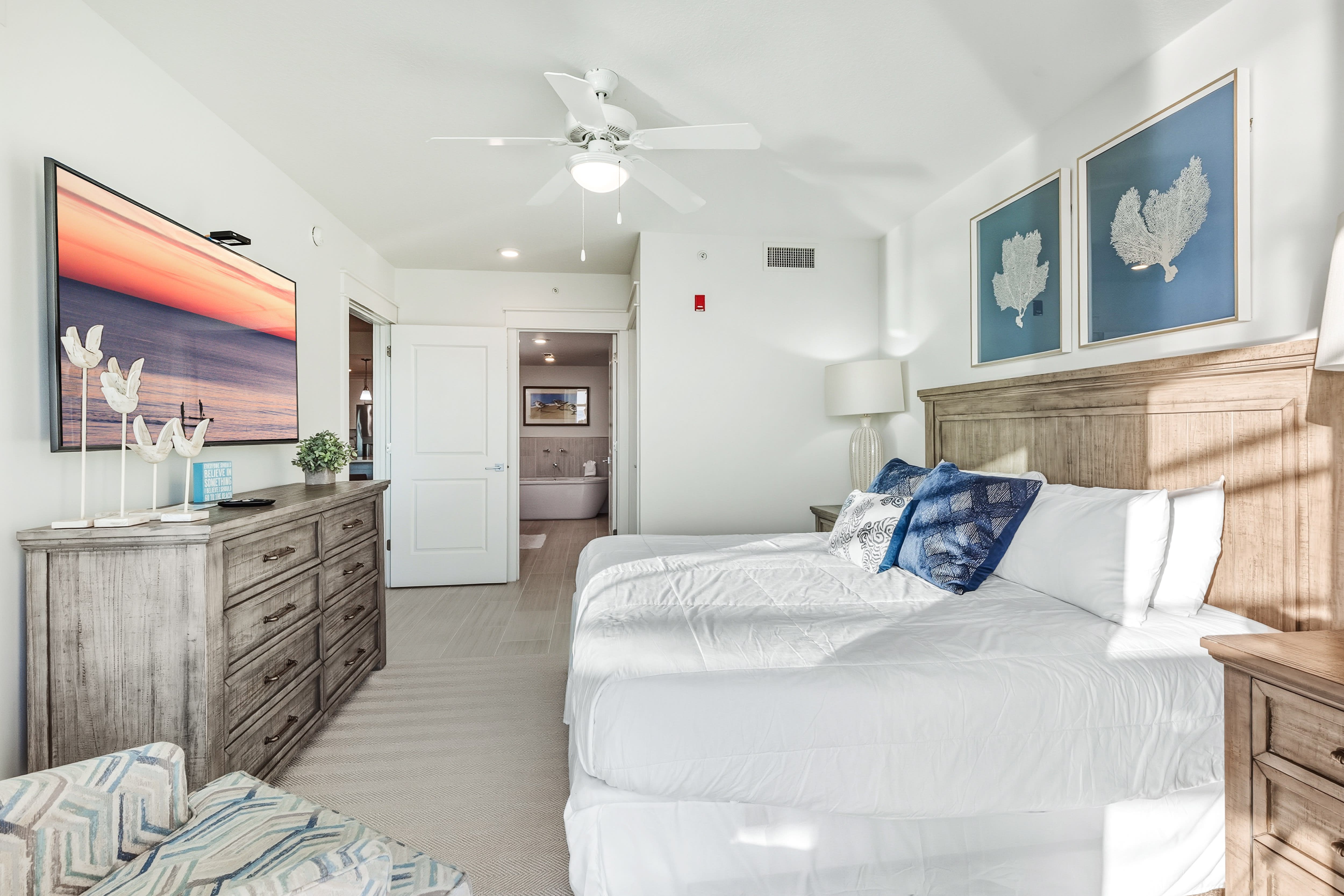 Sink into crisp white linens and coastal charm in your serene bedroom retreat, complete with beach-inspired artwork and modern amenities.