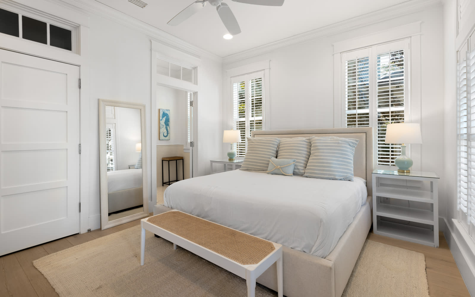 Drift off to peaceful sleep in this bright, airy bedroom where coastal charm meets comfort beneath gentle ceiling fans.
