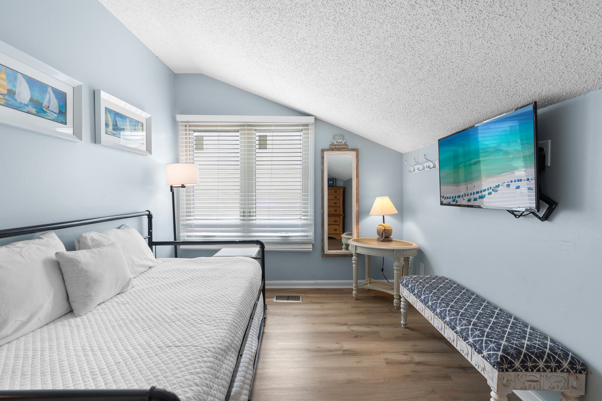 Charming upstairs guest room with a cozy daybed that converts to a king, wall-mounted TV, and stylish coastal décor—perfect for flexible sleeping arrangements.