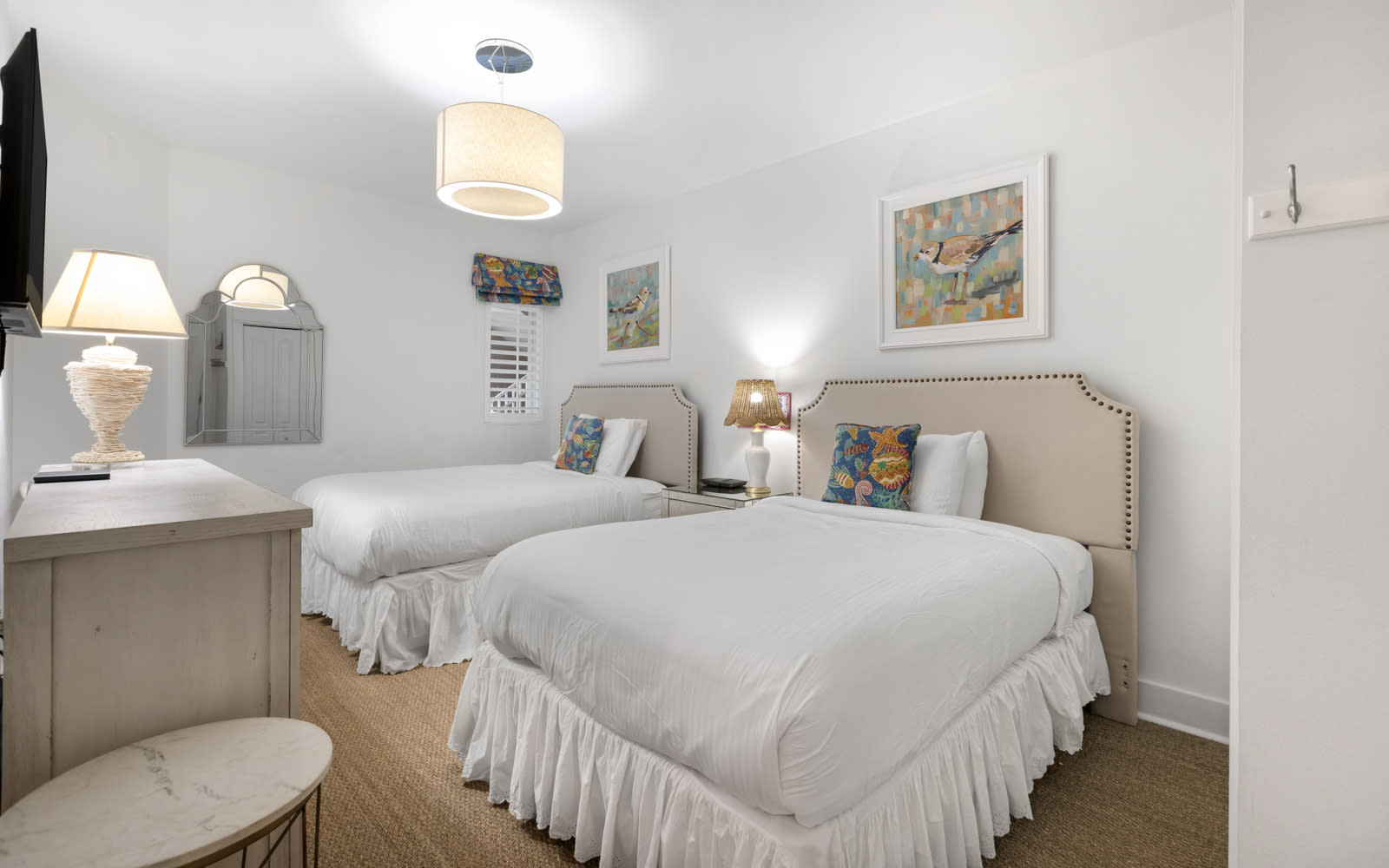 Relax in your bright twin bedroom with crisp linens, charming nautical artwork, and coastal-inspired decor creating a peaceful seaside retreat.