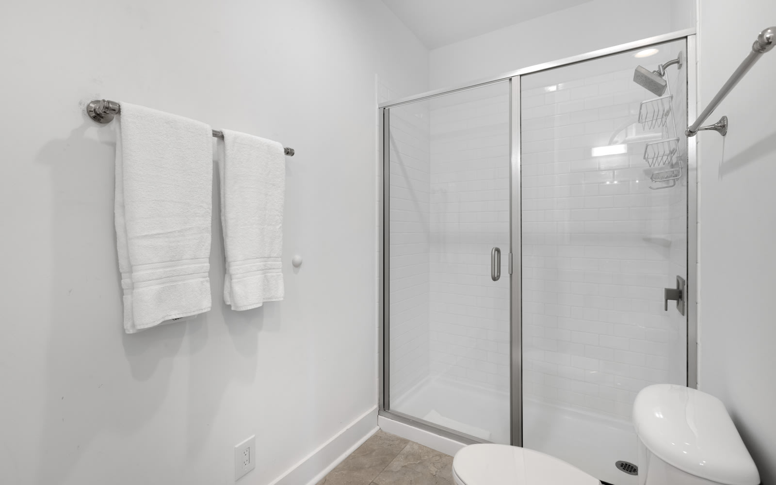 Step into your pristine bathroom featuring a spacious glass-enclosed shower with modern fixtures and fresh towels awaiting your arrival.