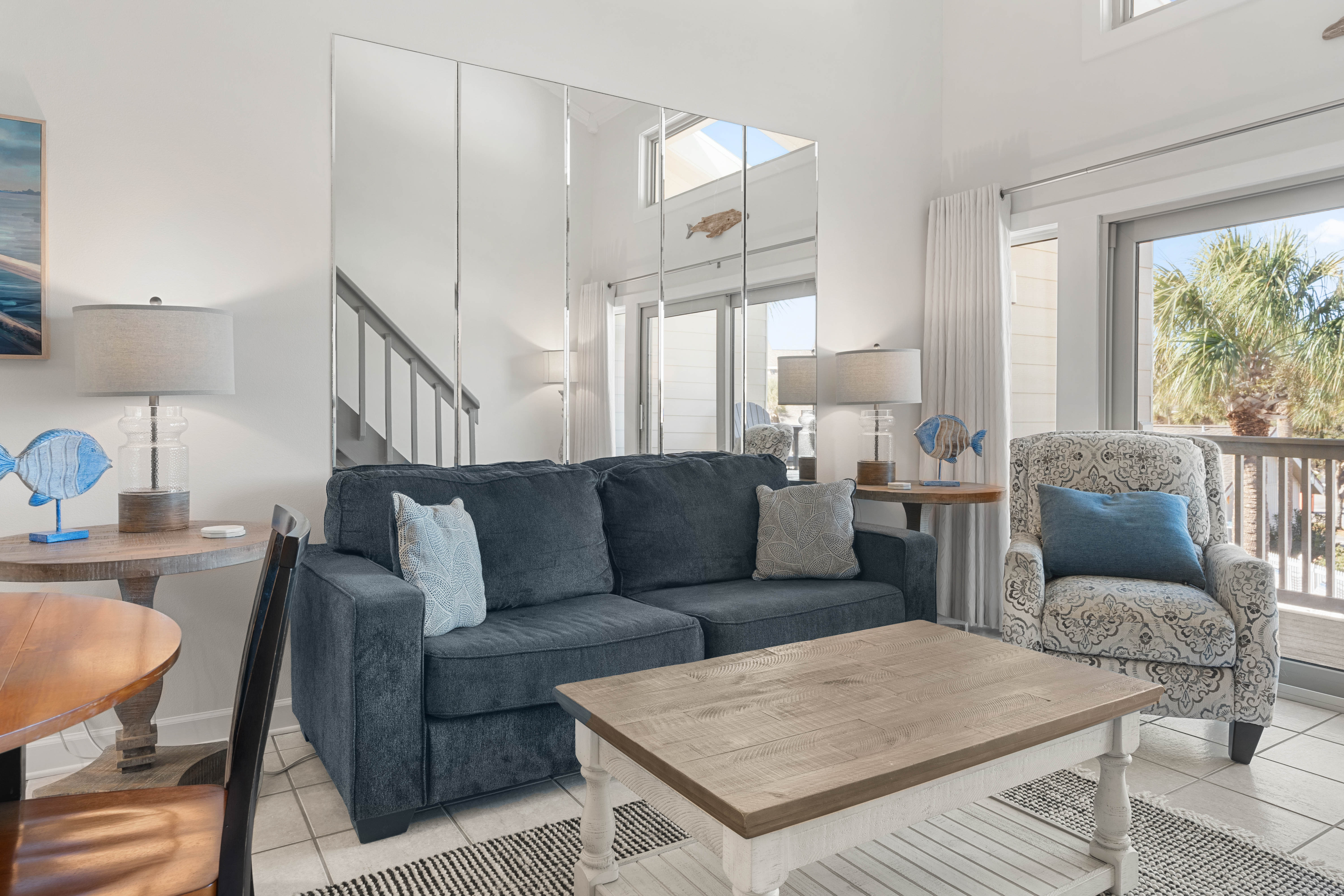 Sink into coastal comfort in your bright living space with stylish furnishings and gentle natural light streaming through large windows.