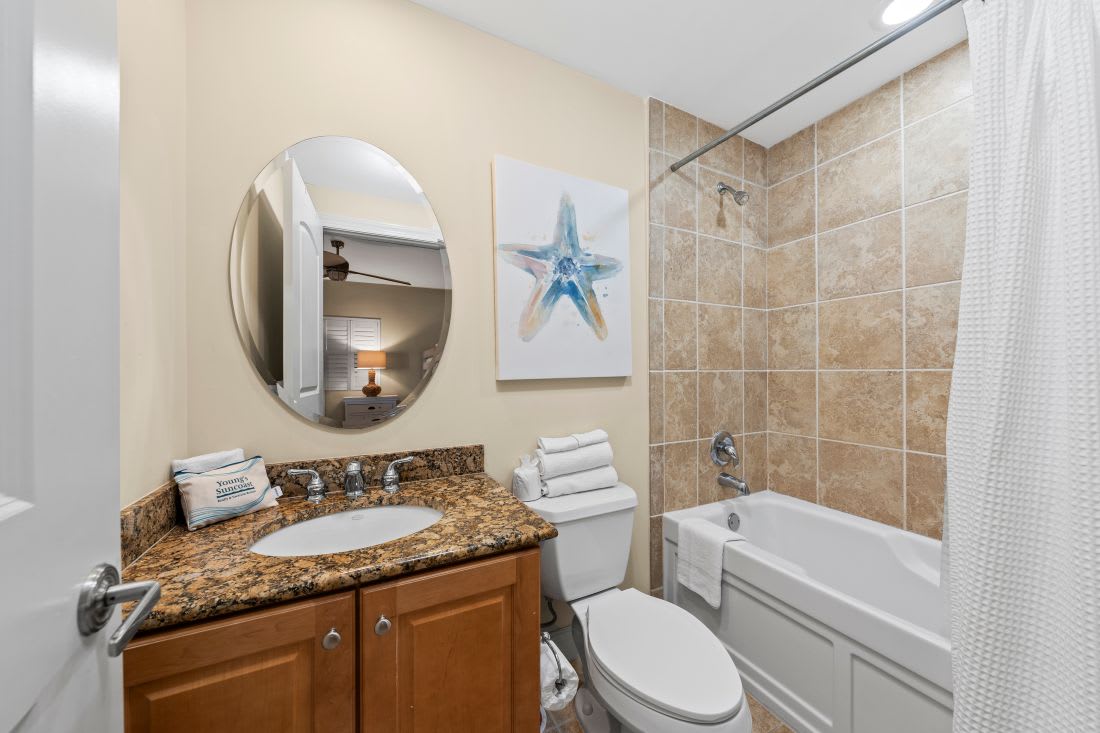 Your private bathroom features granite counters, fresh towels, and a relaxing tub-shower combo with coastal artwork to set the mood.