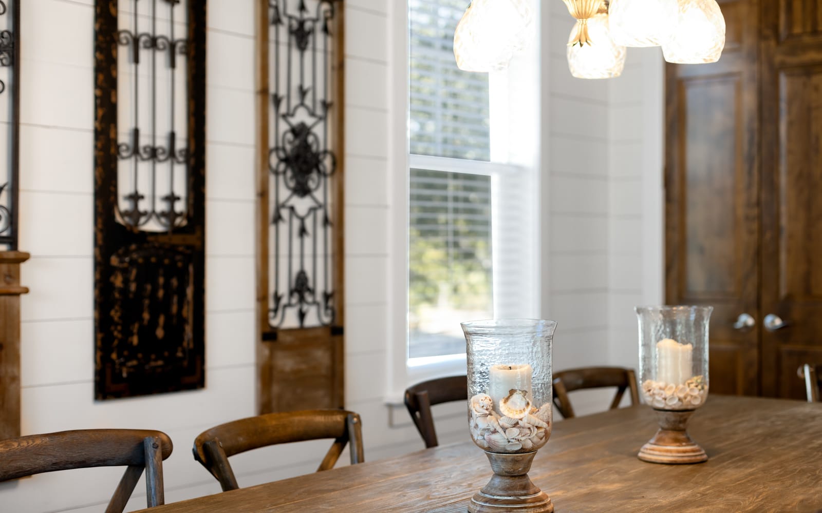 You'll love gathering around this rustic dining table, where candlelit evenings feel magical under warm pendant lighting and elegant ironwork details.