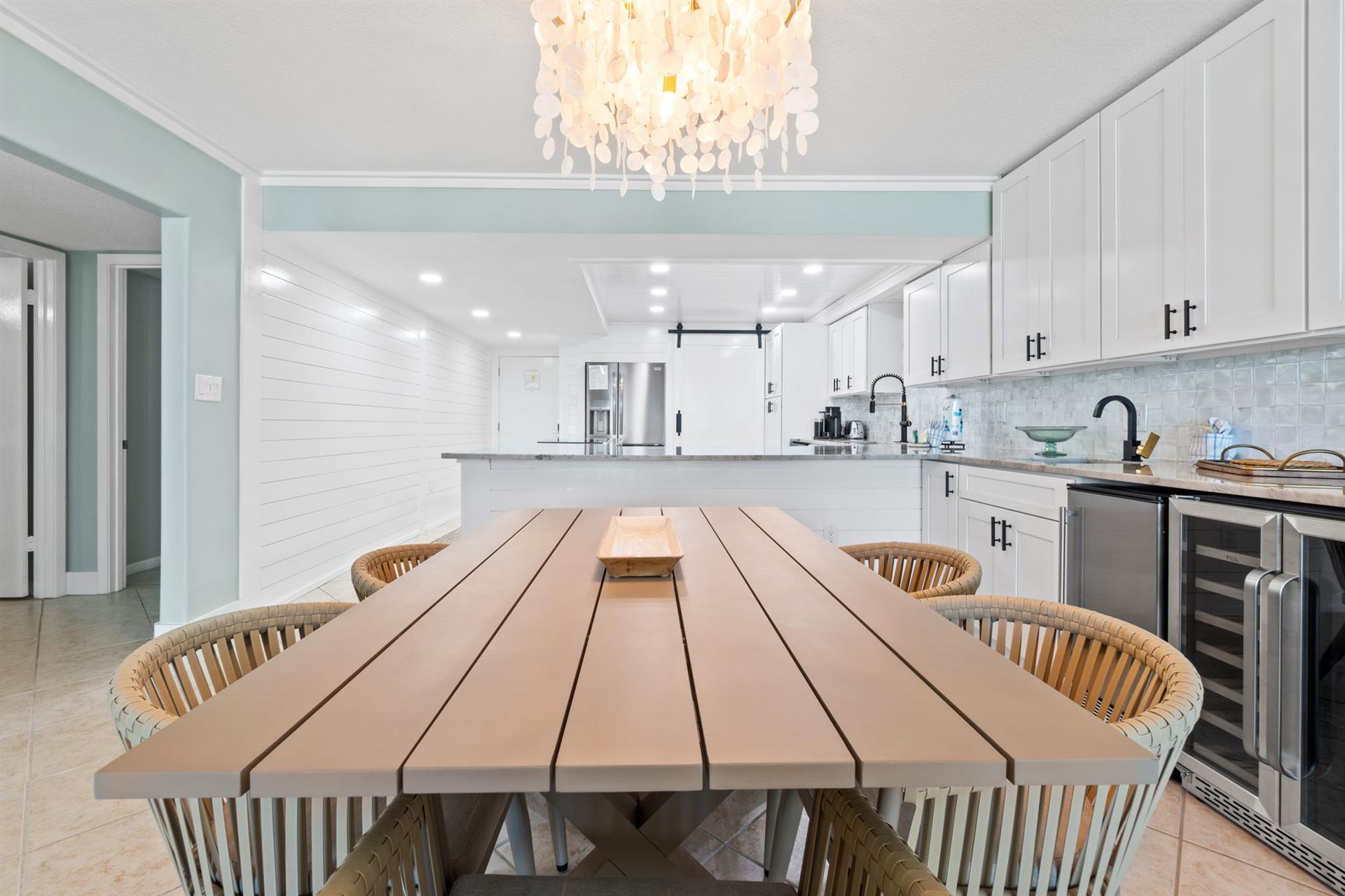 Gather around this stunning dining table where memorable meals unfold beneath elegant chandelier light in your beautiful coastal kitchen.