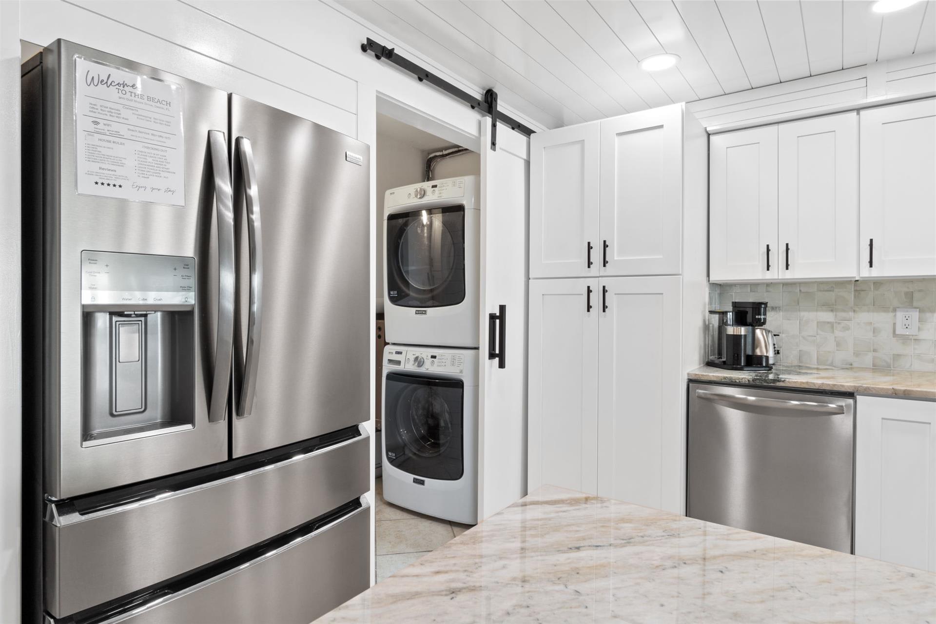 Your pristine white kitchen features stainless steel appliances and convenient laundry tucked behind sleek barn doors.