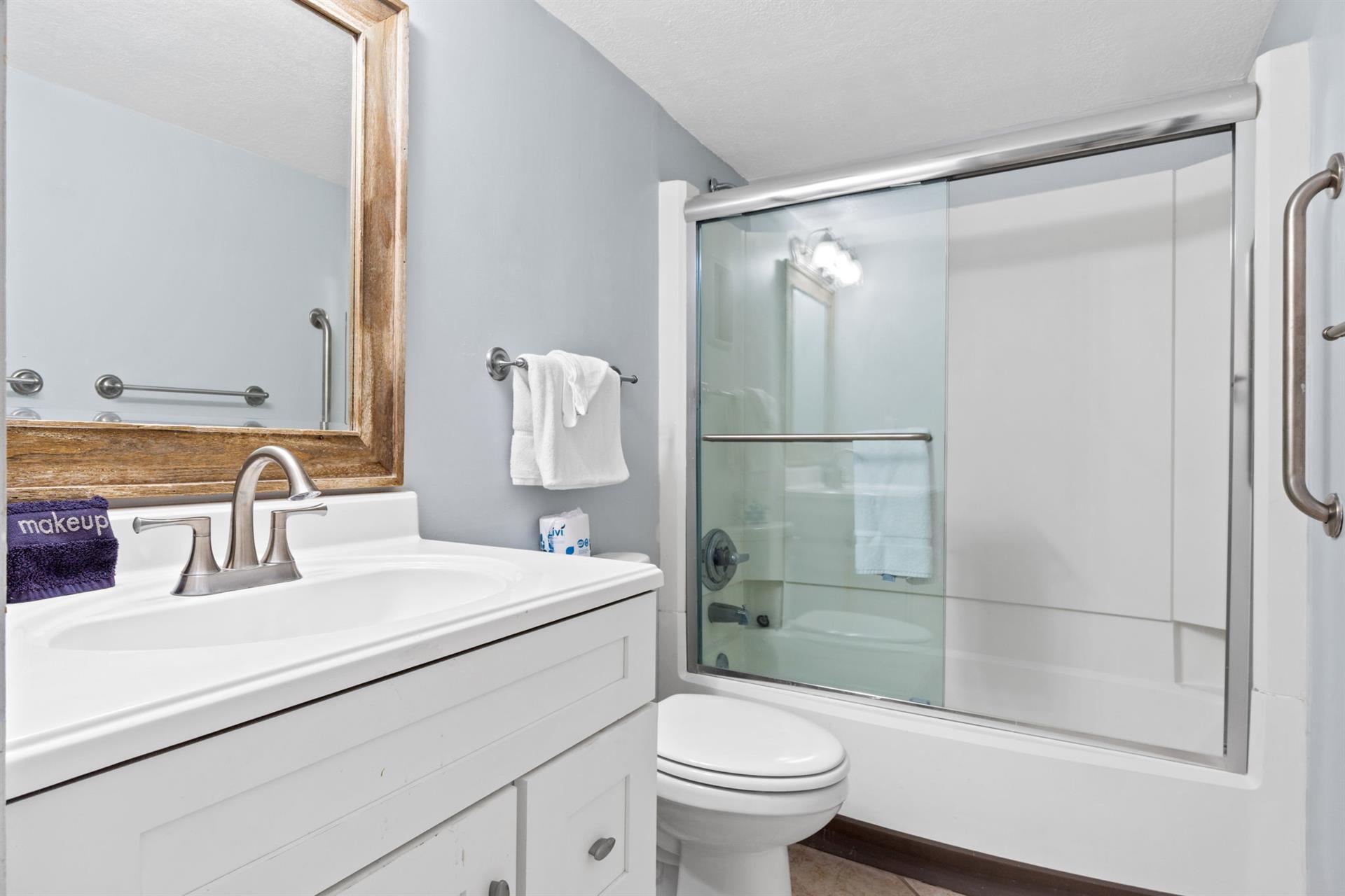 Fresh towels await you in this pristine bathroom with a spacious shower and modern amenities for your comfort.