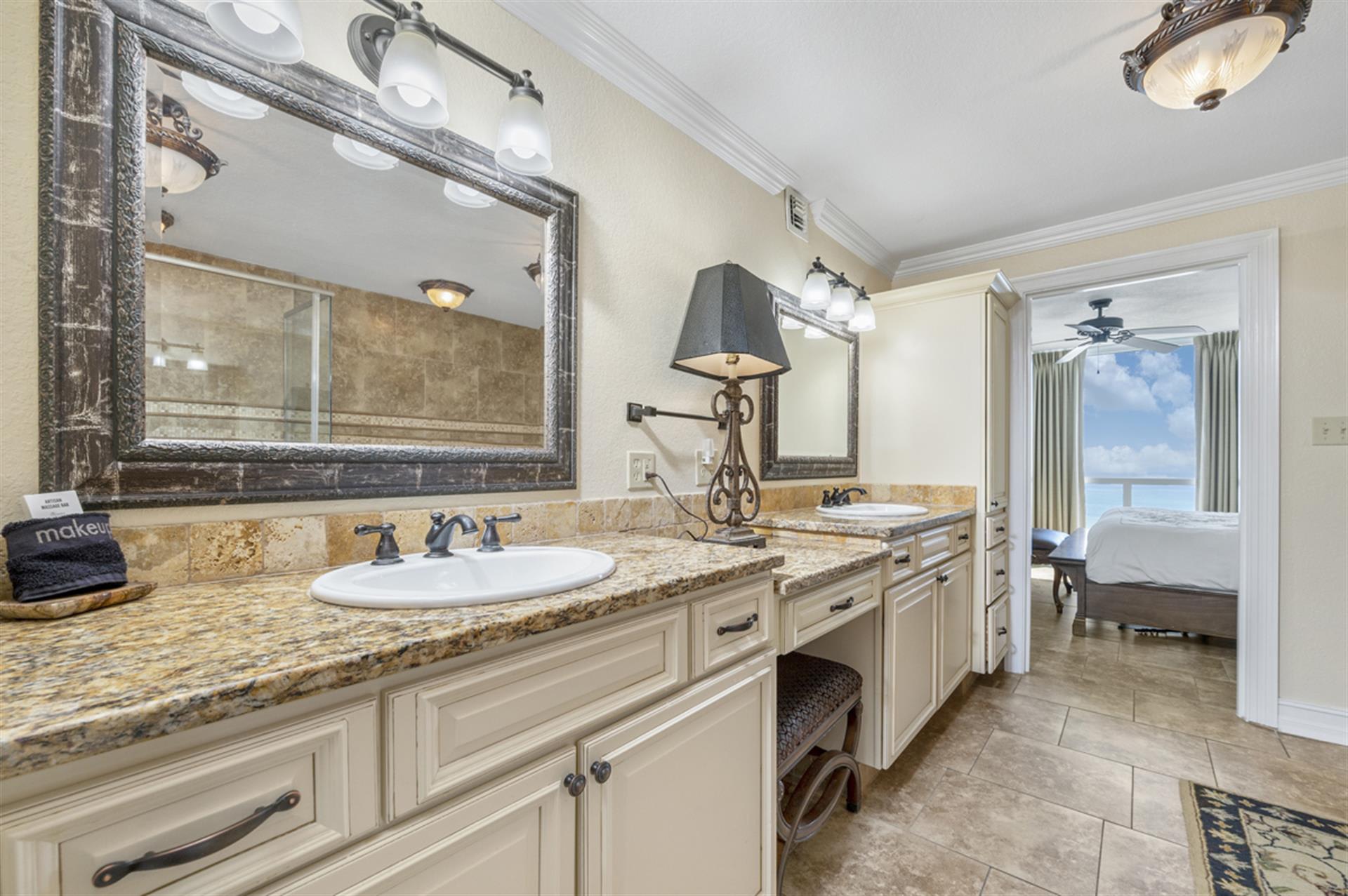 Indulge in your private spa-like bathroom with elegant granite counters, double vanity, and stunning sea views beyond.