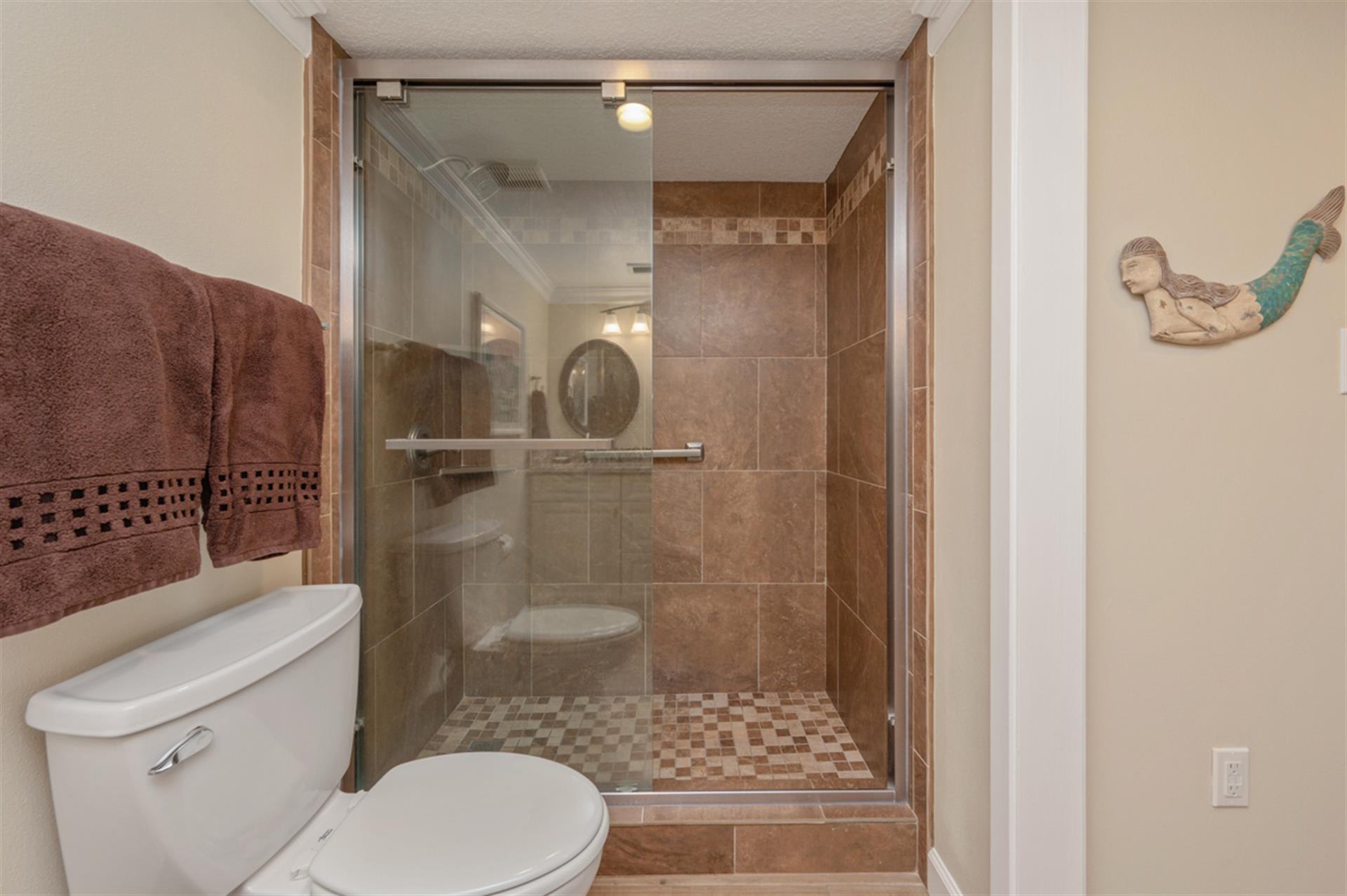 Step into your spa-like bathroom where warm earth tones and elegant tile work create a peaceful retreat for refreshing after beach days.