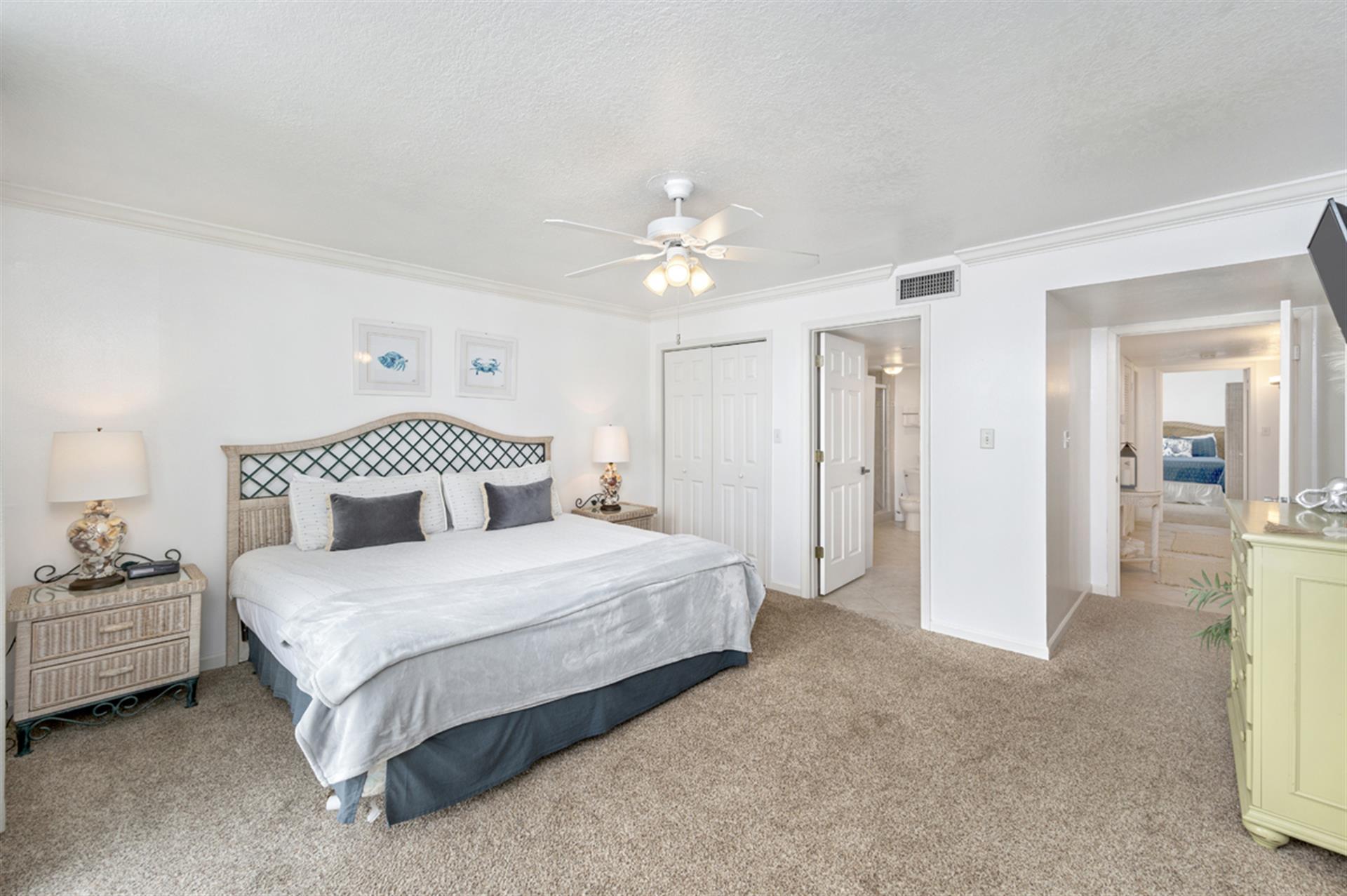 Relax in your peaceful bedroom with coastal charm, featuring a king bed, vintage dresser, and ceiling fan for comfort.