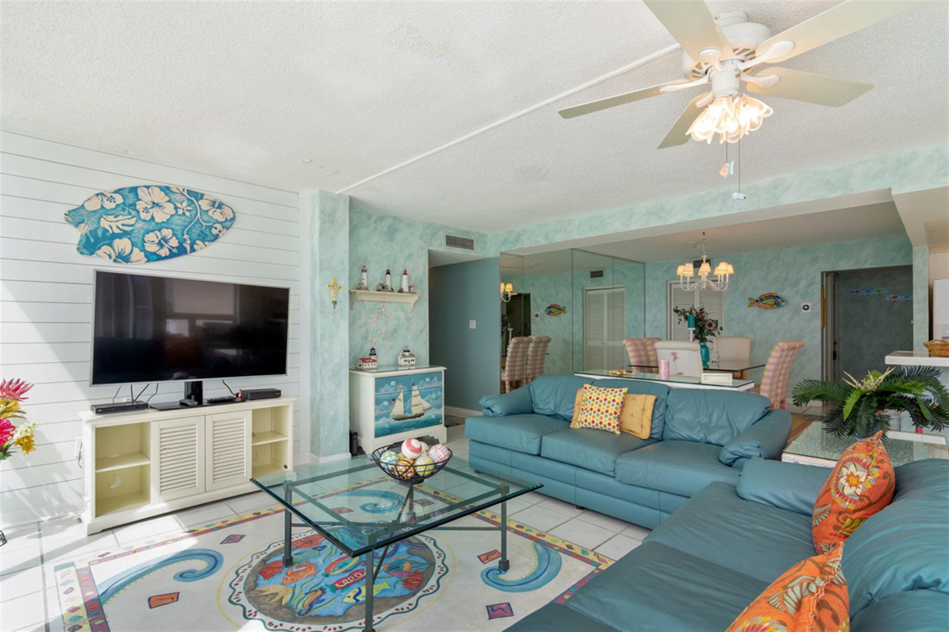 Relax in your tropical-themed living room with ocean blues, cozy seating, and beachy decor creating the perfect coastal retreat ambiance.