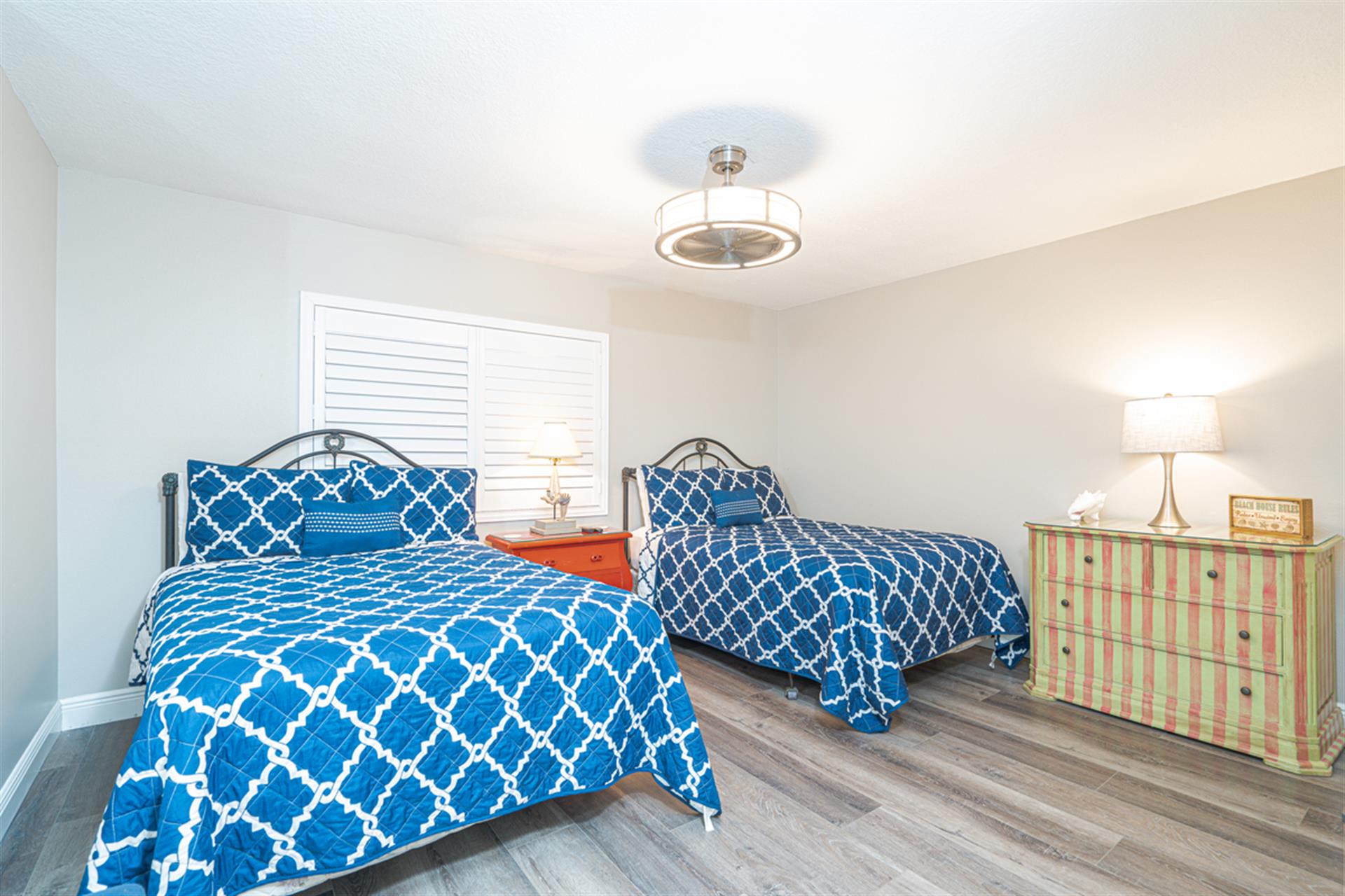 Rest peacefully in your twin bedroom featuring matching blue geometric bedding, hardwood floors, and thoughtful coastal touches.