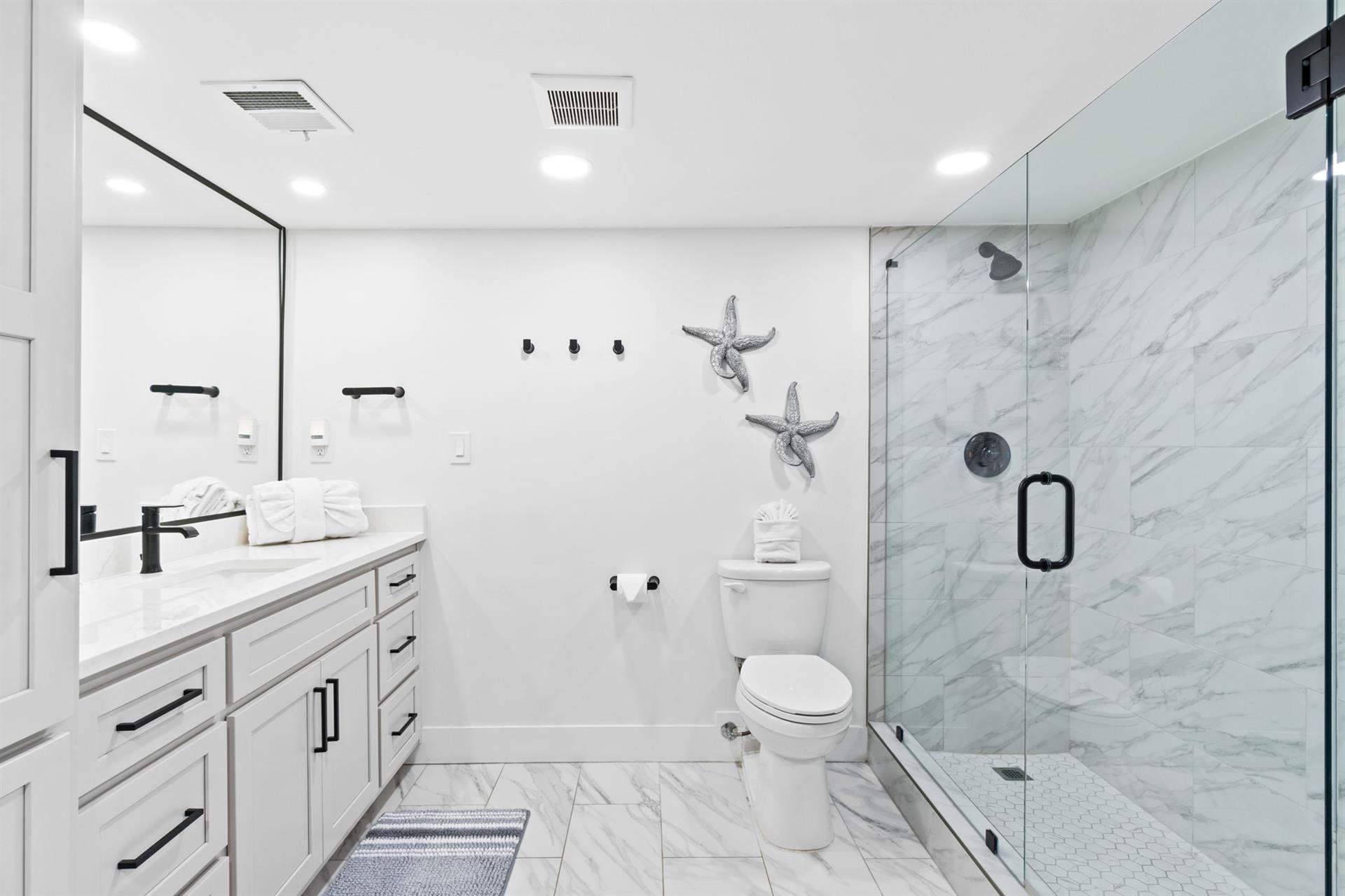 Step into your luxurious marble sanctuary featuring a spacious walk-in shower and elegant coastal touches that make every morning feel like a spa retreat.