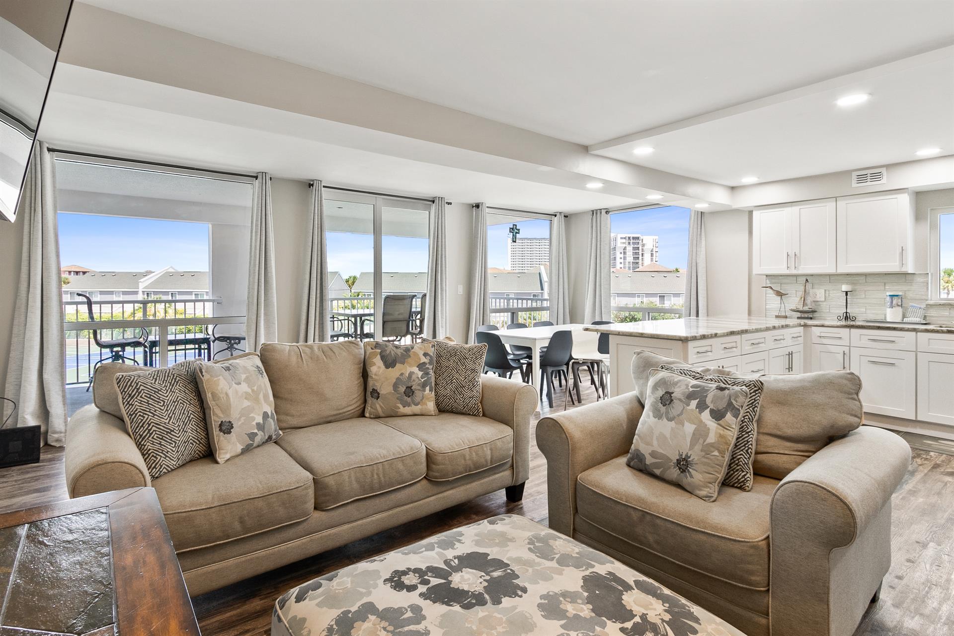 Sink into plush sofas in your bright living space, where city views through floor-to-ceiling windows create the perfect backdrop for relaxation.