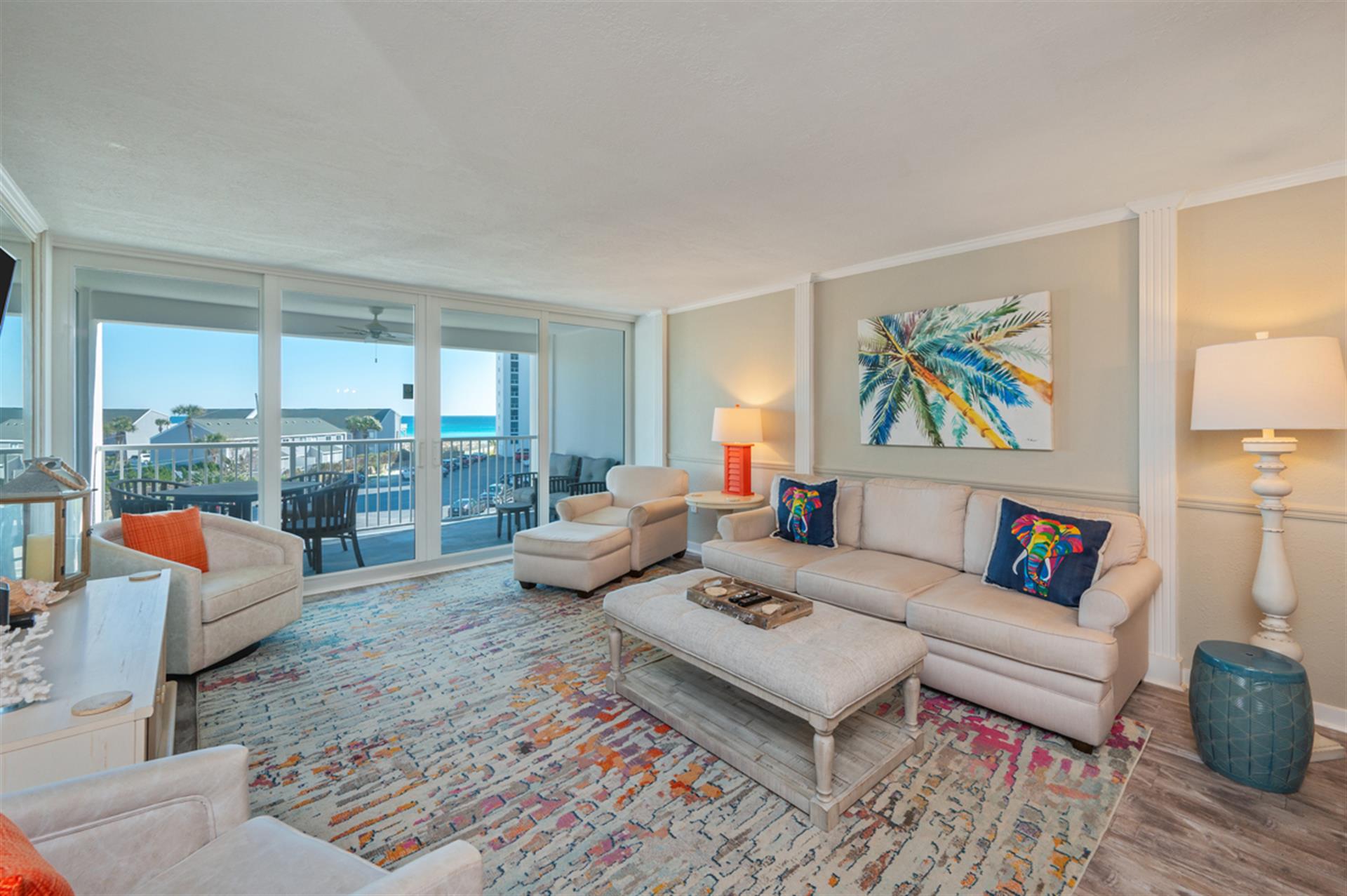 Unwind in your elegant living room where coastal artwork and vibrant rugs create a tropical paradise, while stunning balcony views invite relaxation.