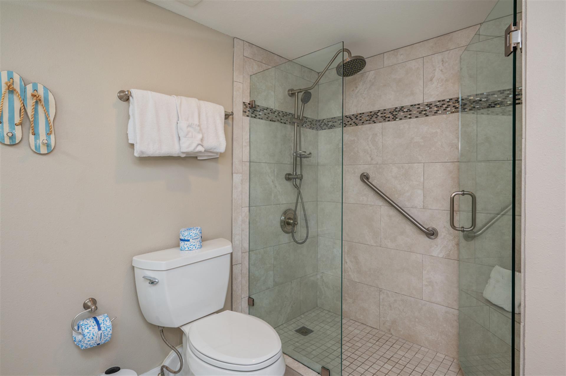 Step into your private spa-like bathroom featuring a spacious glass-enclosed shower with rainfall head and thoughtful accessibility features for ultimate comfort.