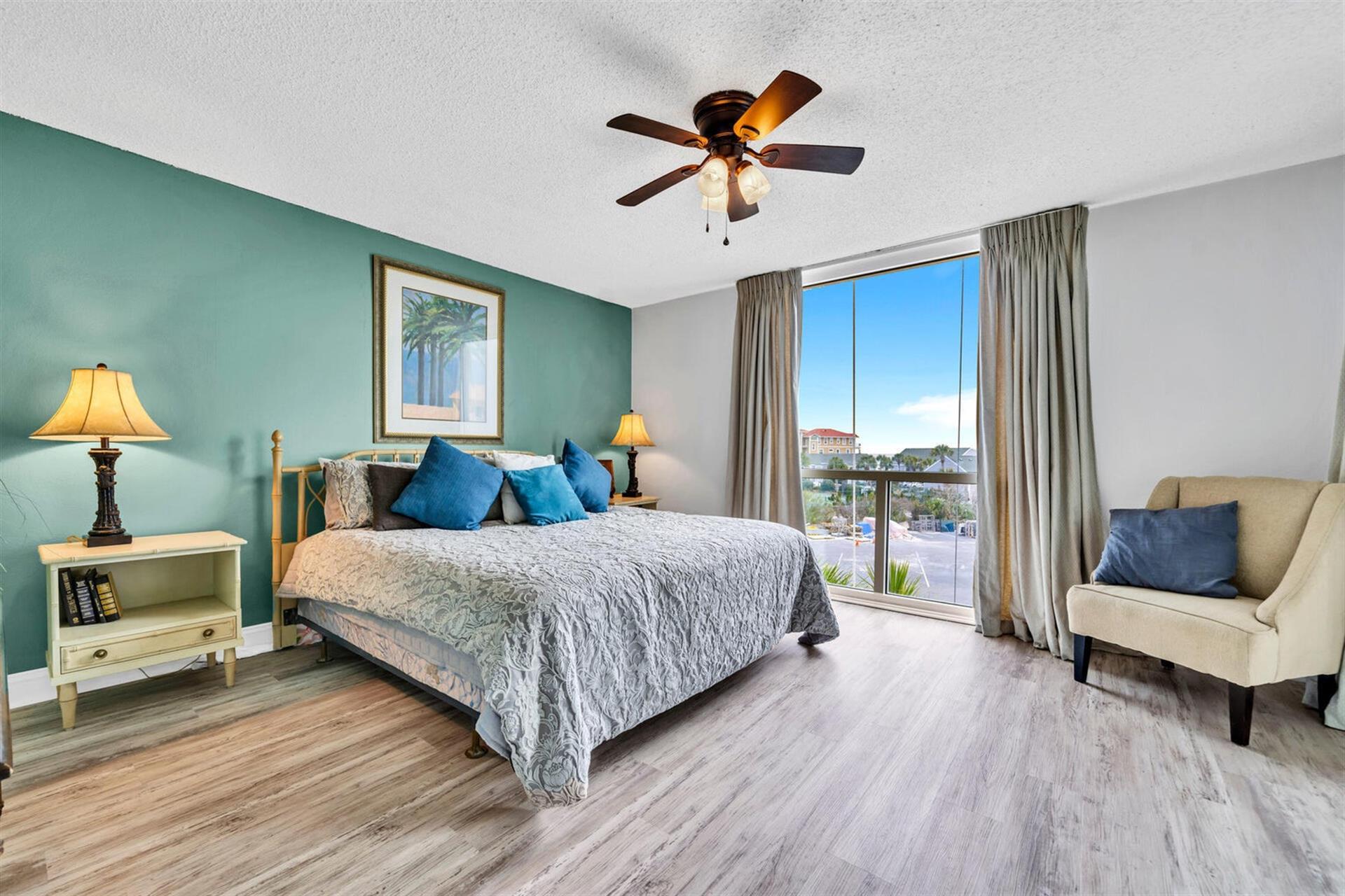 Sink into plush bedding and coastal charm in your spacious bedroom, where morning light reveals beautiful city views through floor-to-ceiling windows.
