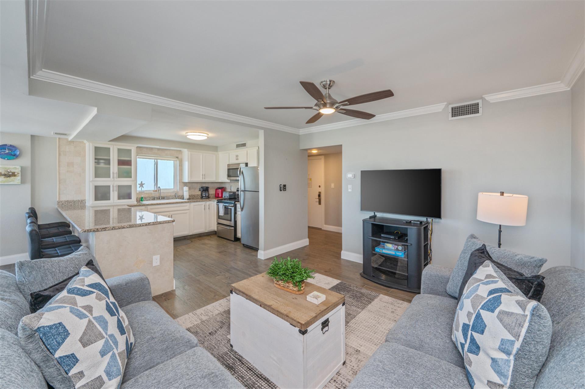 Relax in your open-concept living space with plush seating, modern kitchen, and entertainment center - your coastal getaway awaits.
