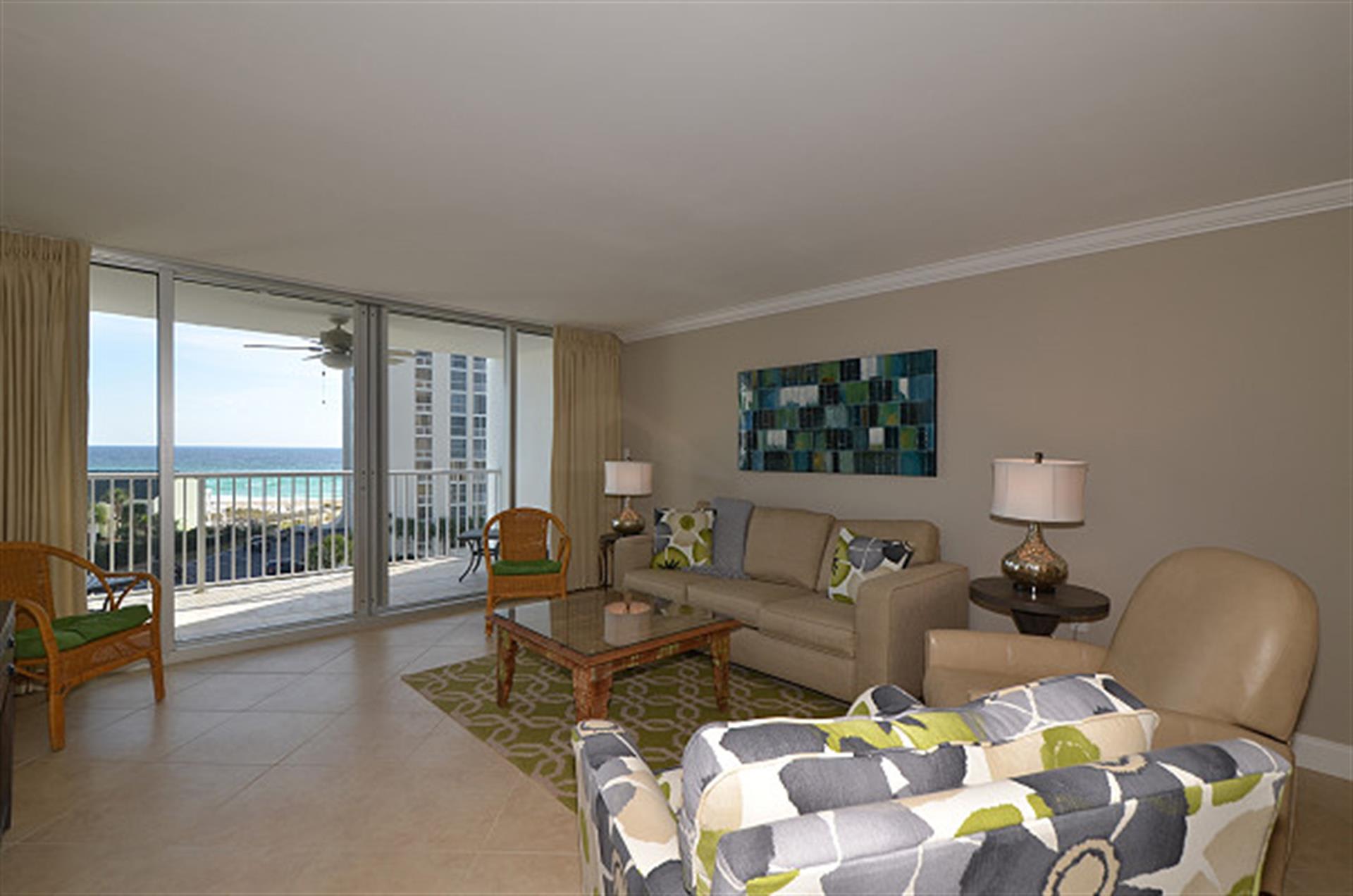 Relax in your bright living space with ocean views through floor-to-ceiling windows and comfortable seating perfect for unwinding.