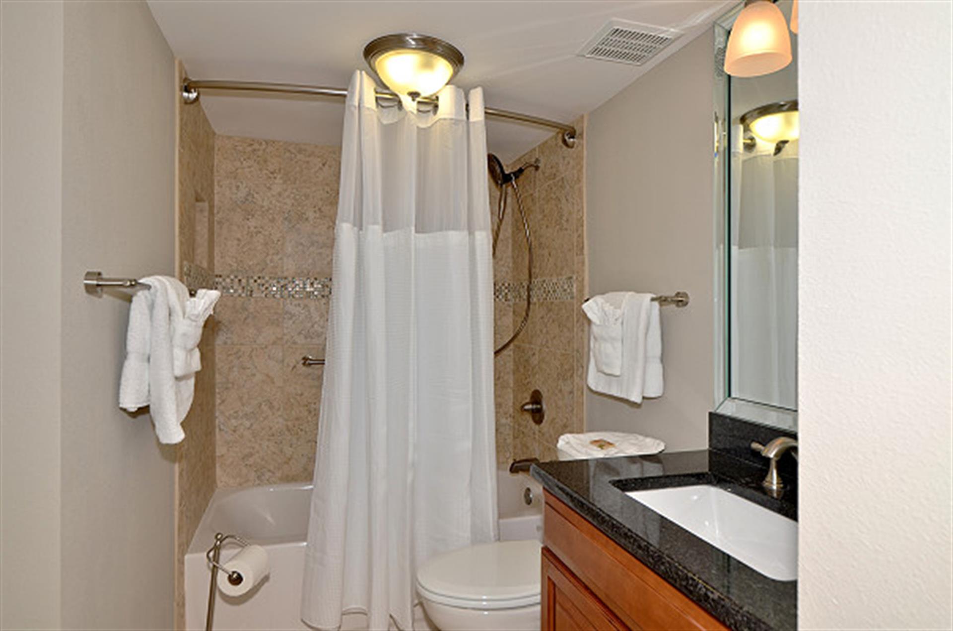Step into your elegant bathroom featuring marble-tiled shower, granite counters, and plush towels for your comfort.