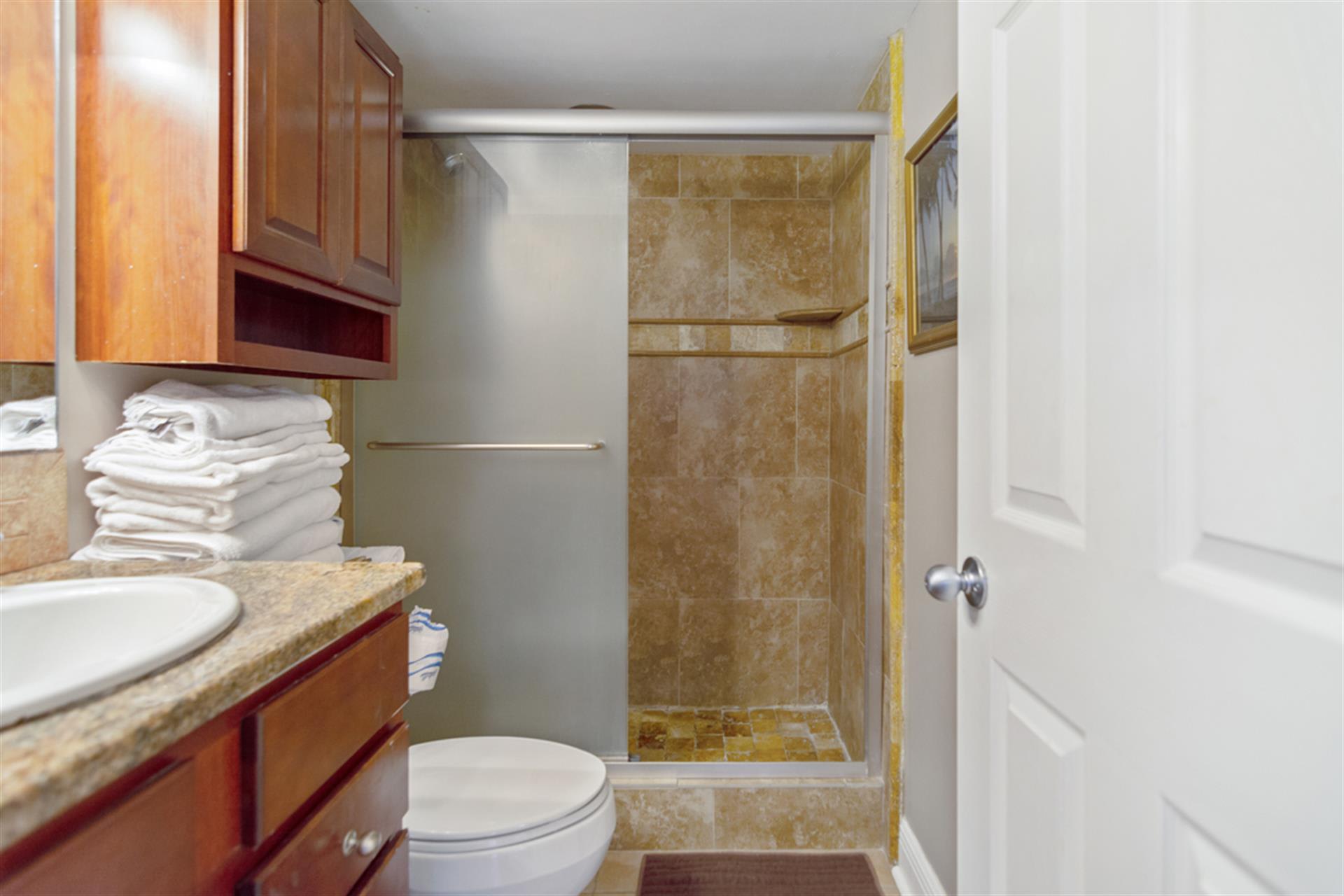 Refresh in your elegant bathroom featuring travertine tile shower, granite counters, and plush towels waiting for you.