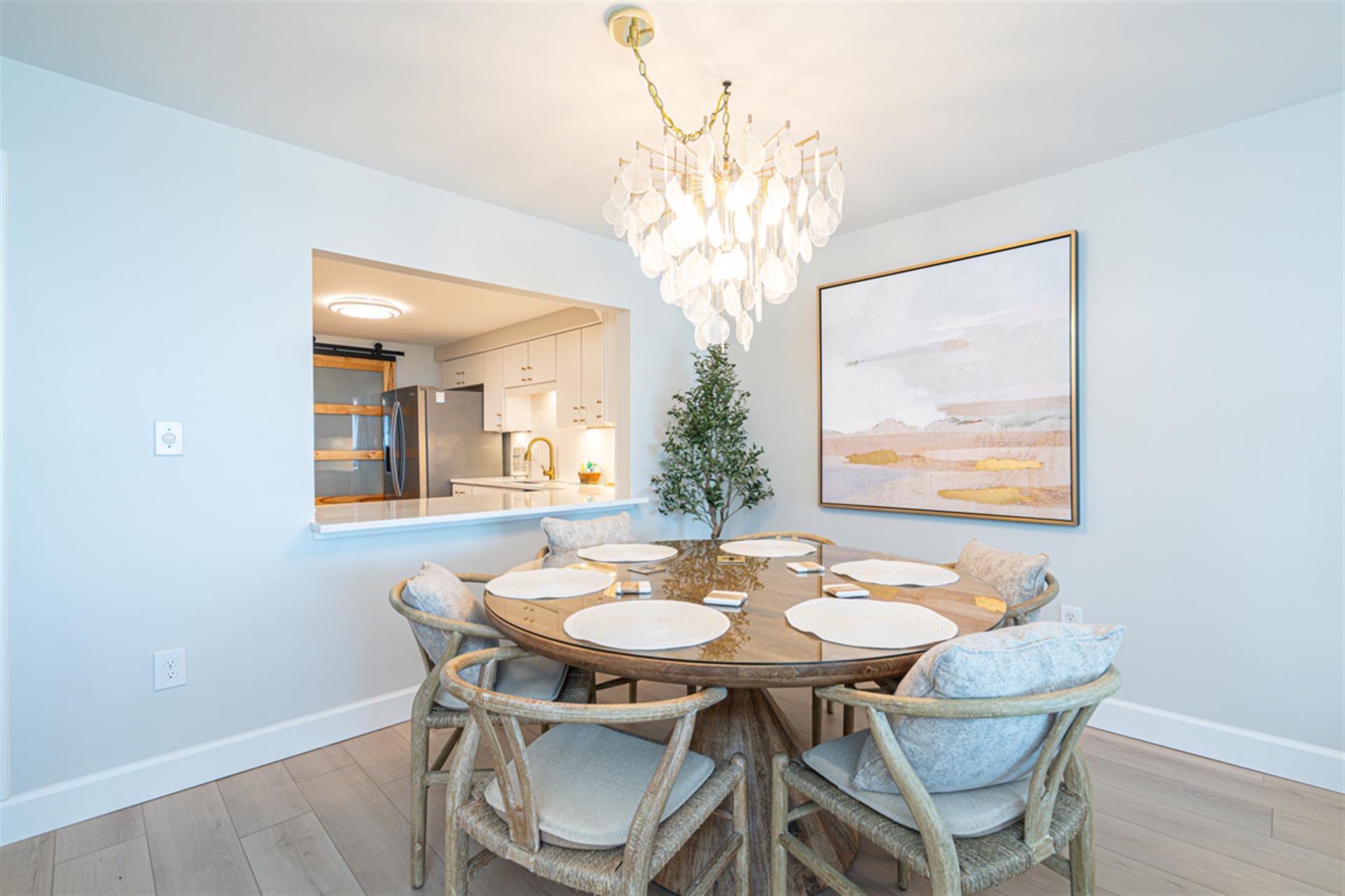 Gather around your elegant dining table under soft chandelier light, with the modern kitchen just steps away for easy entertaining.