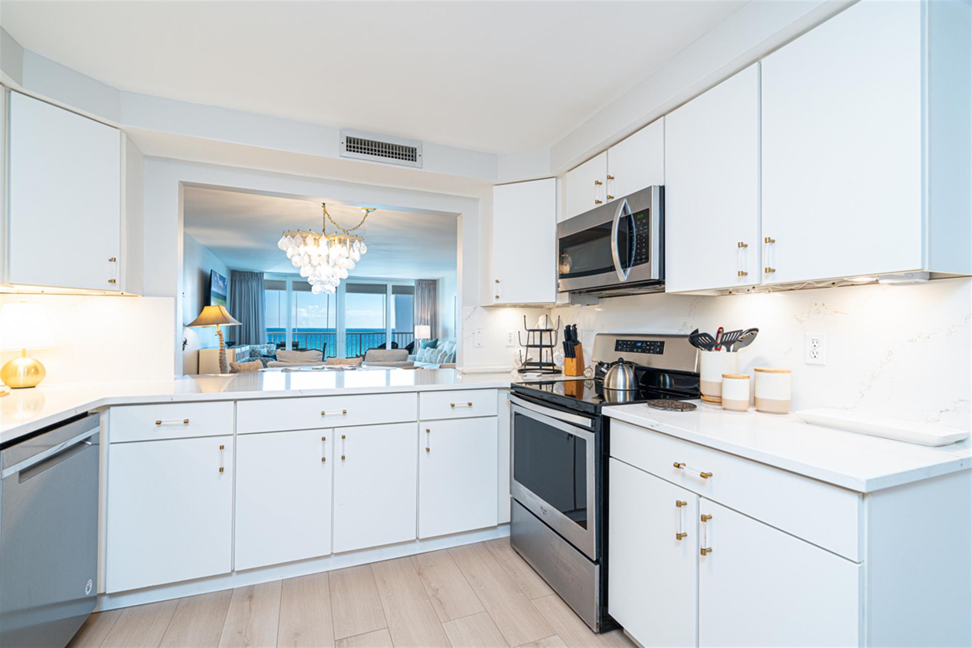 Your elegant kitchen opens to breathtaking ocean views, featuring modern appliances and pristine white cabinetry perfect for preparing memorable meals.
