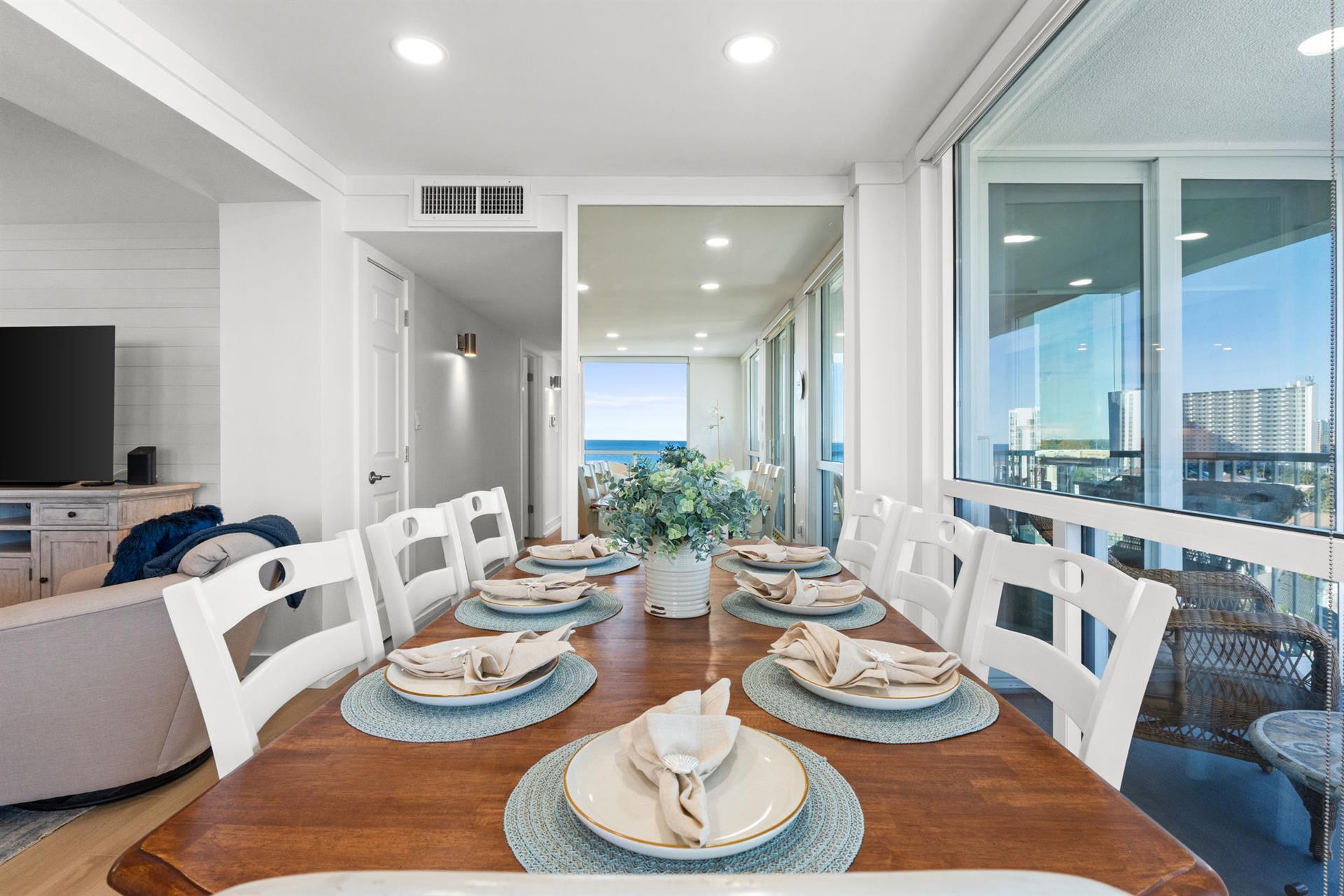 Gather around your elegant dining table, perfectly set for memorable meals while gazing at stunning city and ocean views through floor-to-ceiling windows.