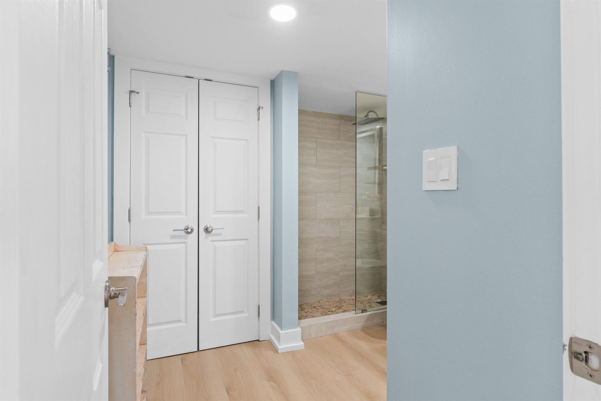 Step into your serene bathroom featuring soothing blue walls and a spacious glass-enclosed shower with beautiful stone tiles.