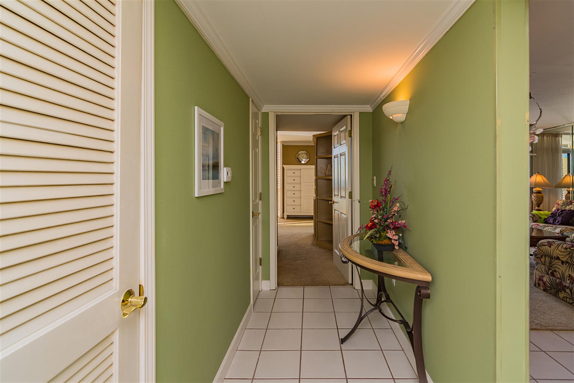 Step into your welcoming hallway where soothing green walls and warm lighting create an inviting path to your comfortable rooms.