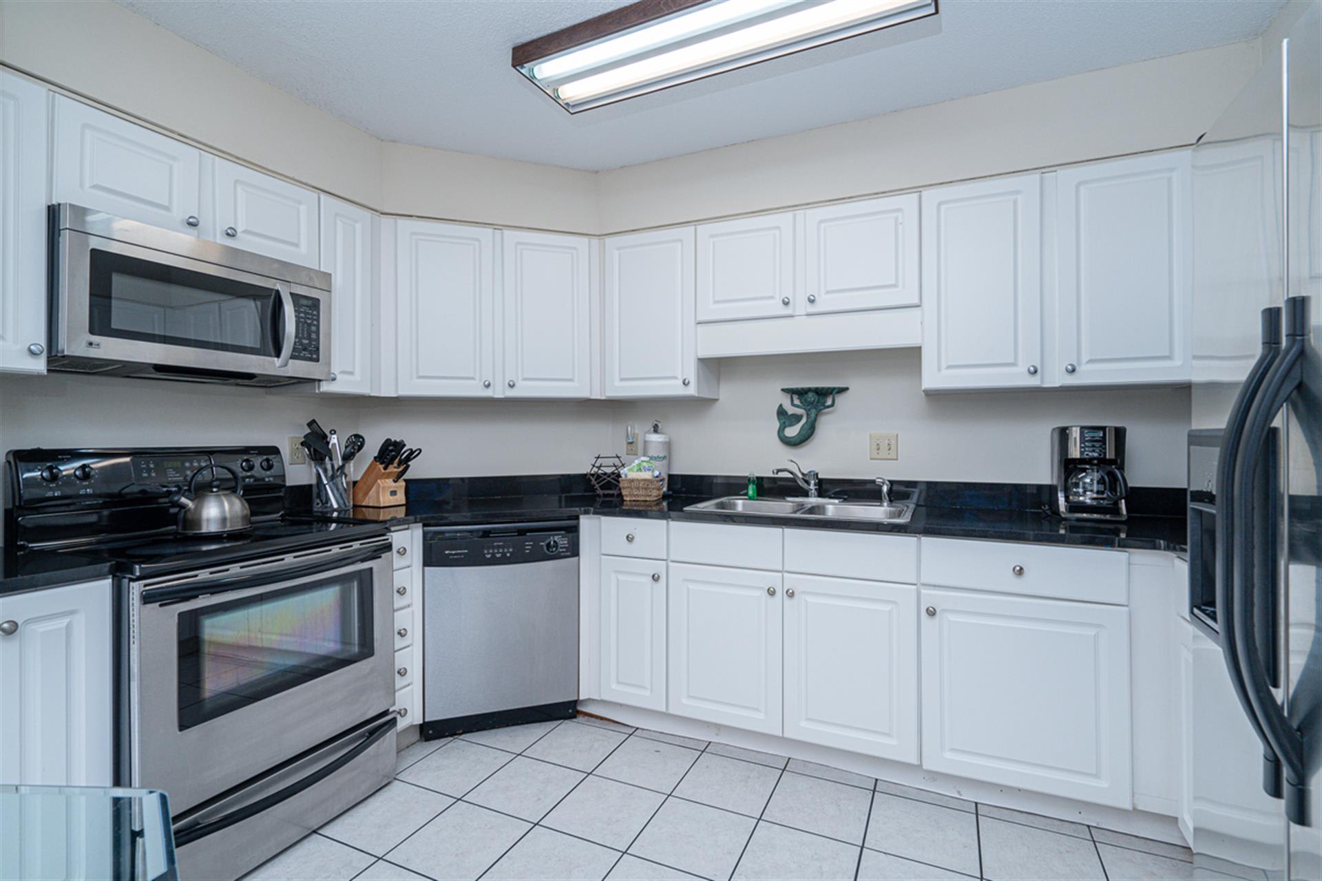 Your fully equipped kitchen features crisp white cabinets, granite countertops, and stainless steel appliances, perfect for preparing family meals during your stay.