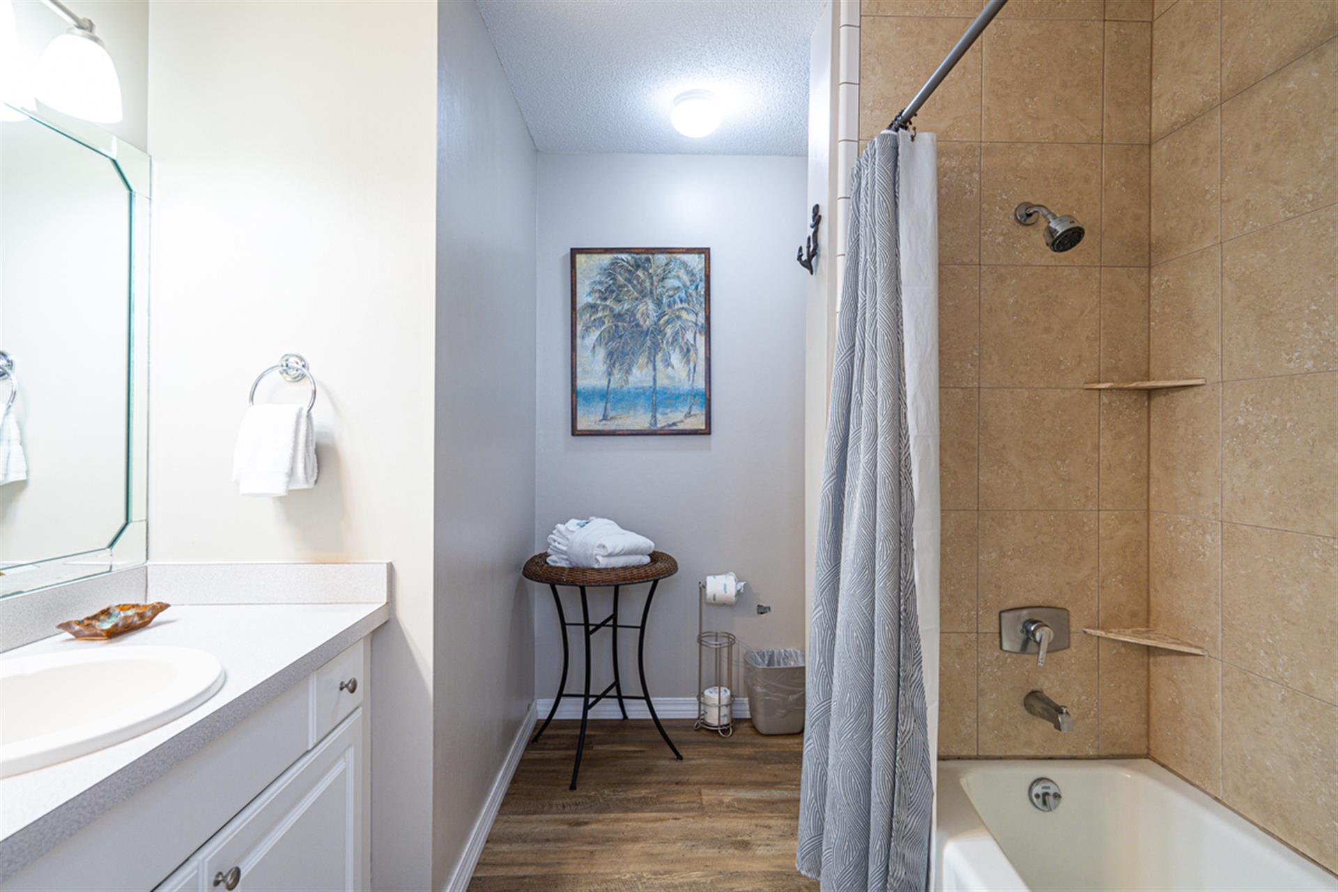 Unwind in your spa-like bathroom with a deep soaking tub, rainfall shower, and coastal artwork creating tranquil vibes.