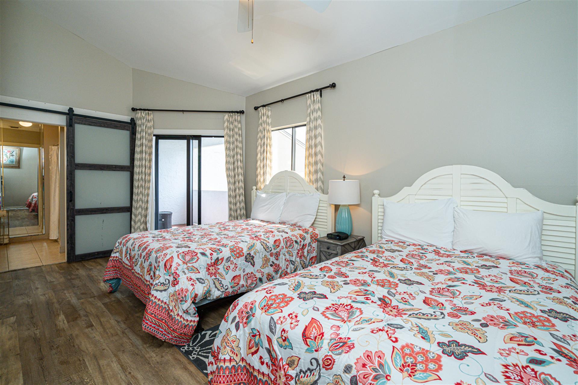 Sink into comfort with two plush beds adorned in vibrant floral linens, where natural light streams through elegant curtains.