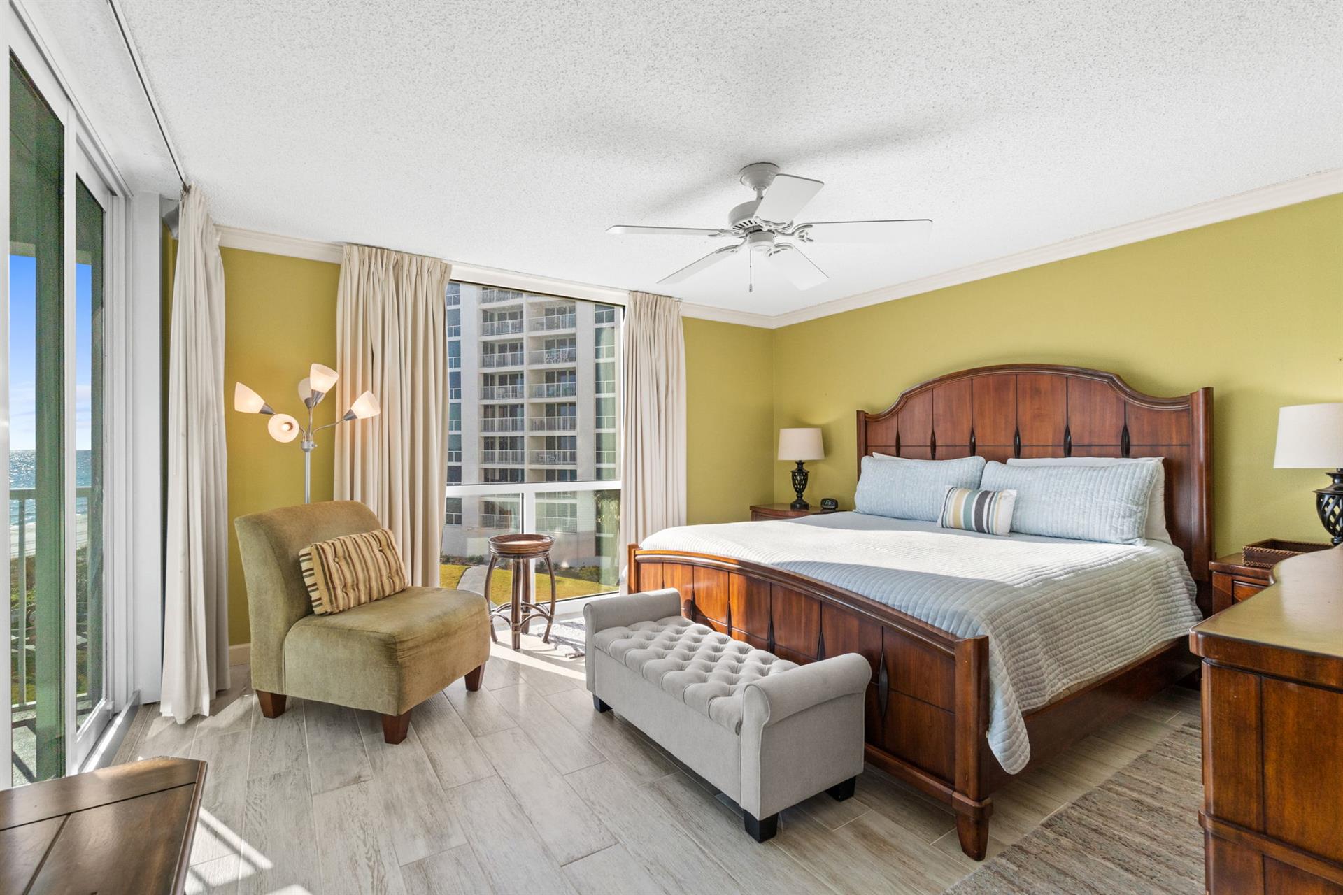 Relax in your spacious bedroom with rich wood furnishings, cozy seating, and bright city views from floor-to-ceiling windows.