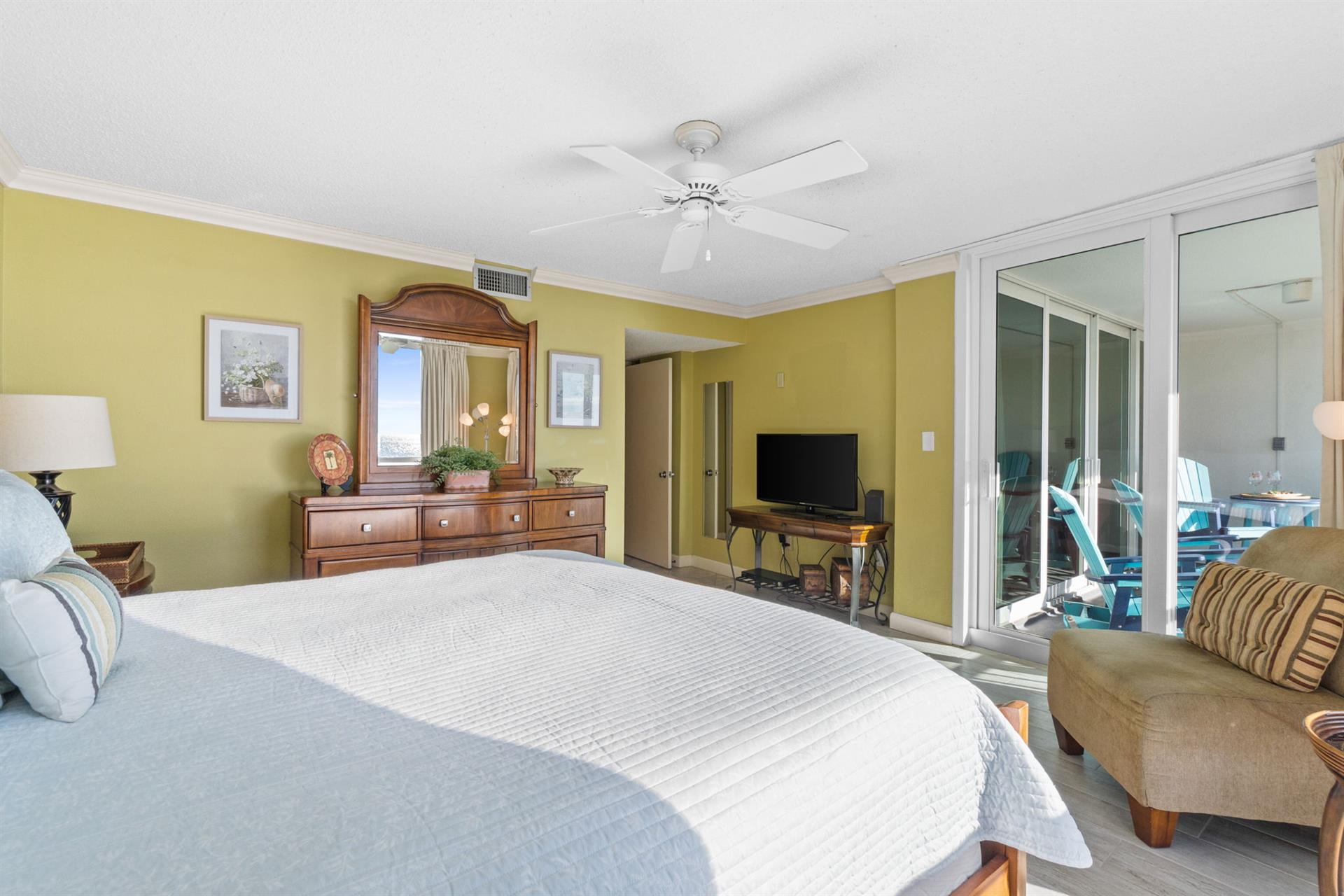 Unwind in your bright bedroom sanctuary with cheerful walls, ceiling fan comfort, and balcony access to ocean breezes.