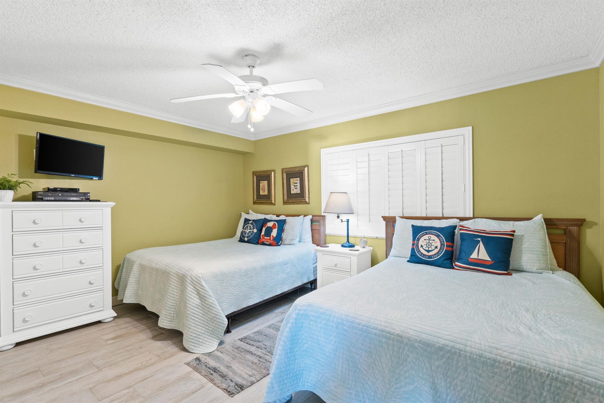 Settle into your coastal-themed bedroom with two comfortable beds, gentle ceiling fan, and nautical touches that create the perfect seaside retreat.