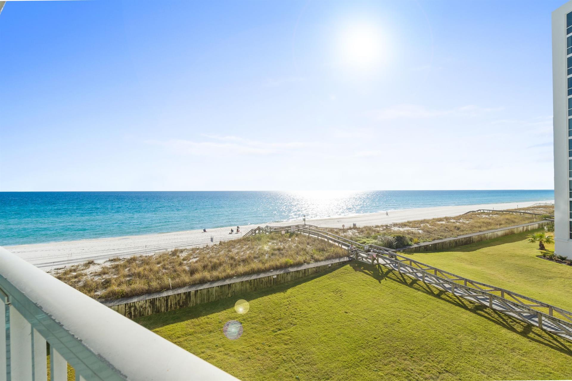 Stunning beachfront vista with pristine white sand, turquoise waters, and coastal walkways stretching along the shoreline.