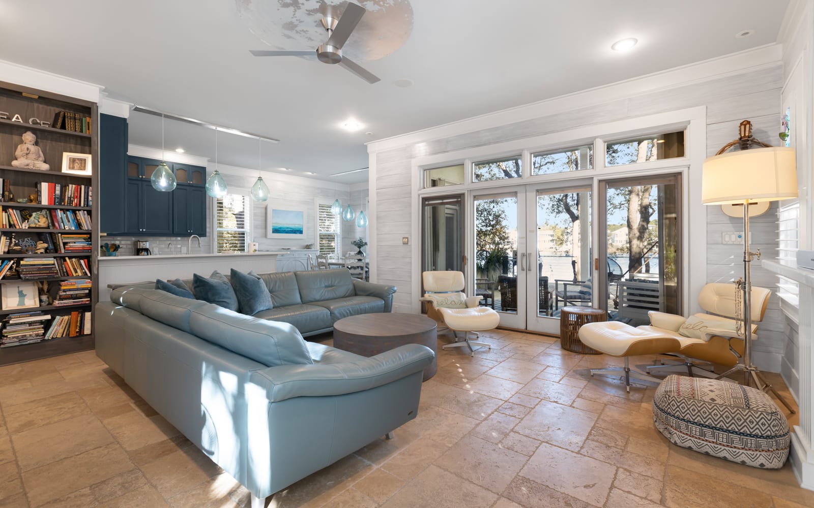 Sink into plush blue sectional seating while natural light streams through French doors, creating your perfect reading nook with built-in bookshelves nearby.