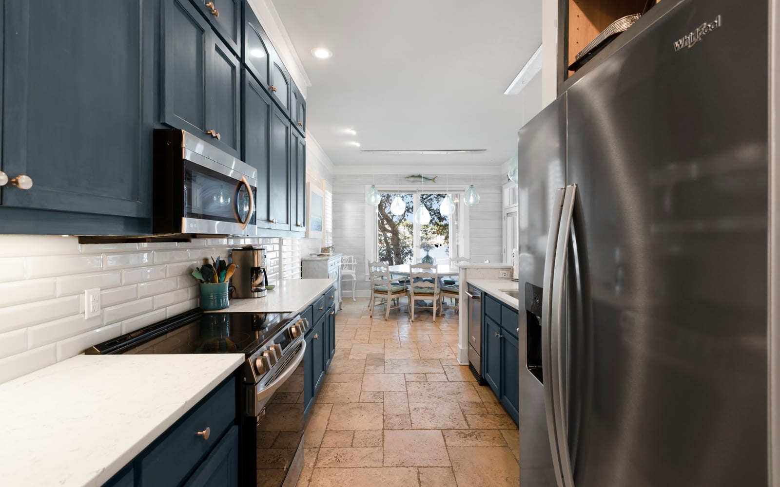 Cook memorable meals in your stylish galley kitchen, featuring sleek navy cabinets, stainless steel appliances, and bright subway tile backsplash.