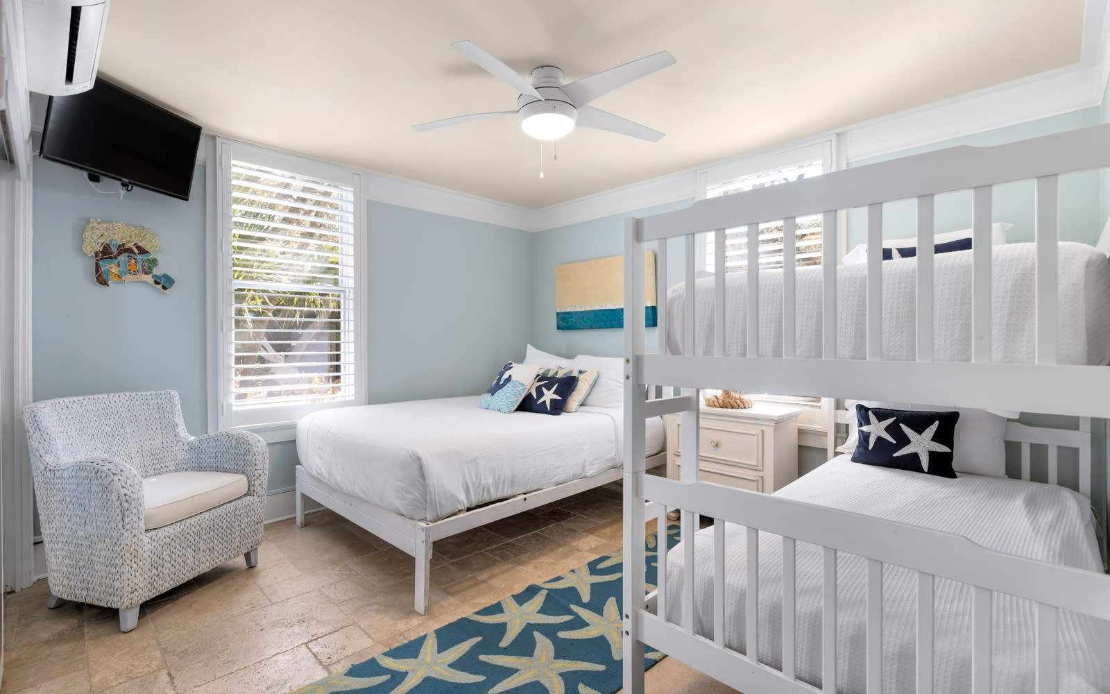 Your coastal-themed bedroom features crisp white bunk beds and nautical decor, creating a serene retreat where ocean breezes flow through plantation shutters.