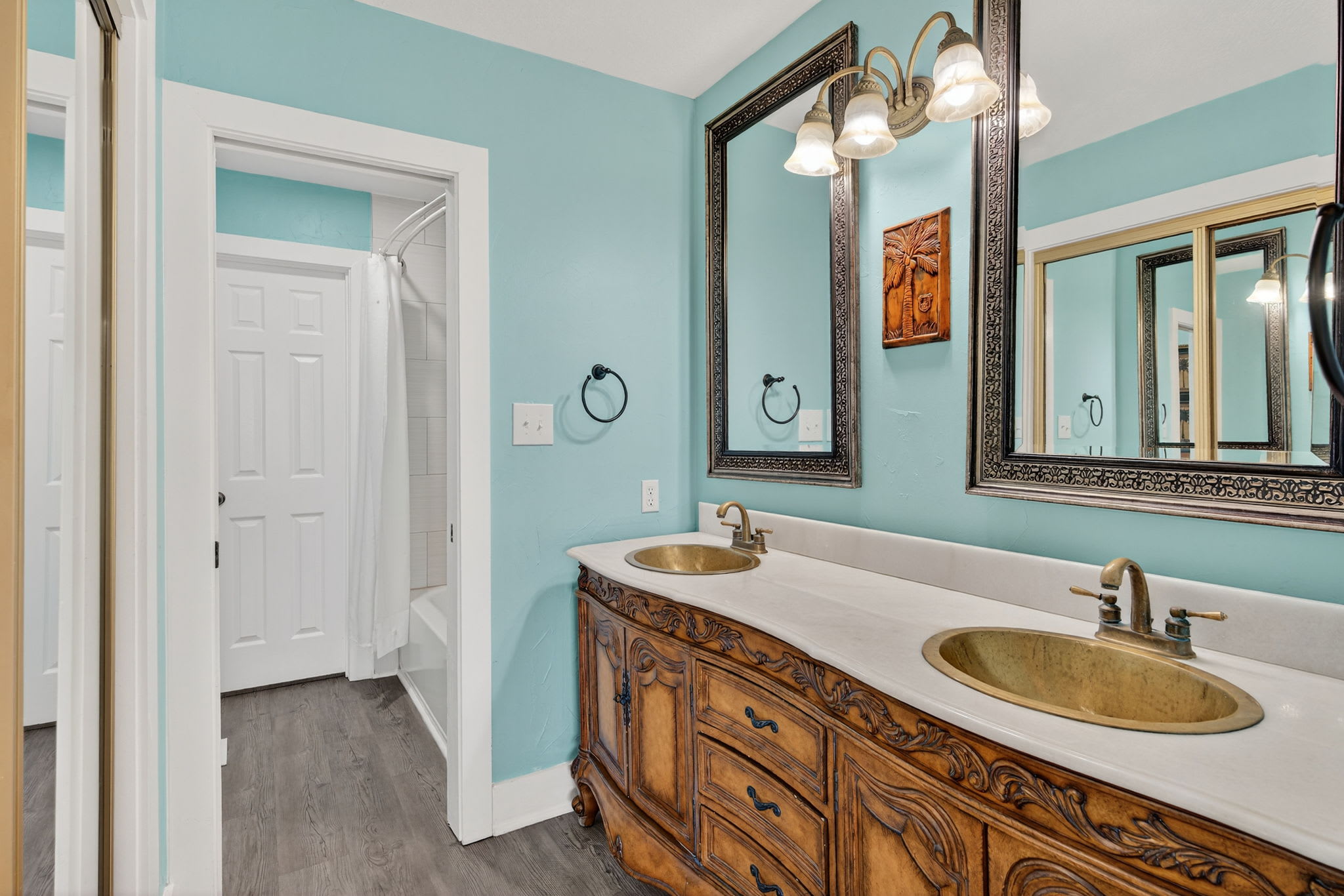 Your elegant bathroom features dual vanity sinks with ornate wooden cabinetry and soothing turquoise walls for a refreshing start to your day.