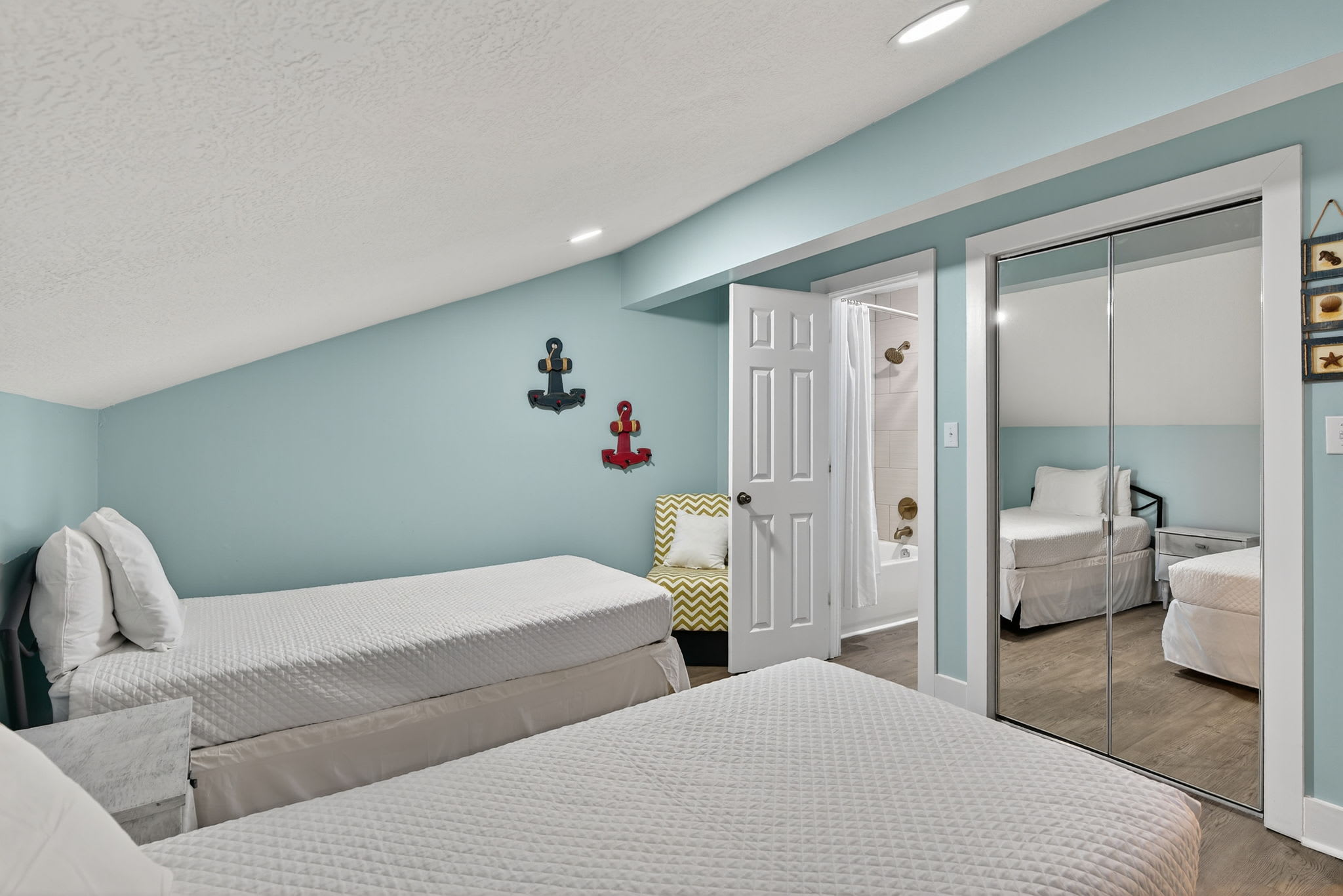 Relax in this charming nautical-themed bedroom featuring twin beds with crisp linens, coastal décor, and a convenient ensuite bathroom for your comfort.