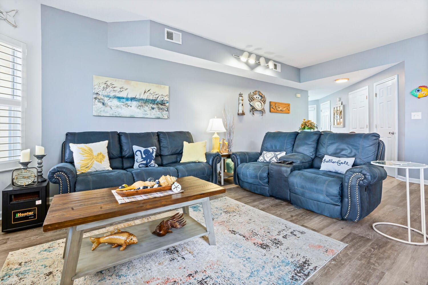 Sink into plush blue recliners in your spacious living room, where coastal artwork and warm lighting create the perfect retreat.